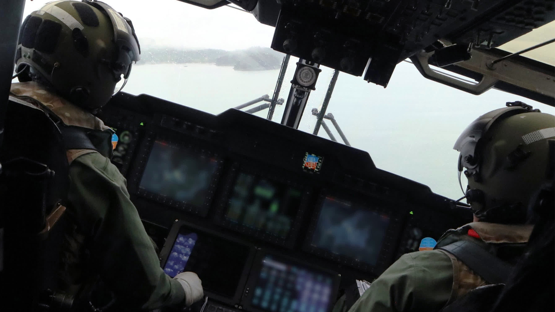 The two pilots keep a sharp eye out for any sign of the Norwegian and German subs as their Merlin banks right over one of the fjords near Bergen (Picture: MOD)