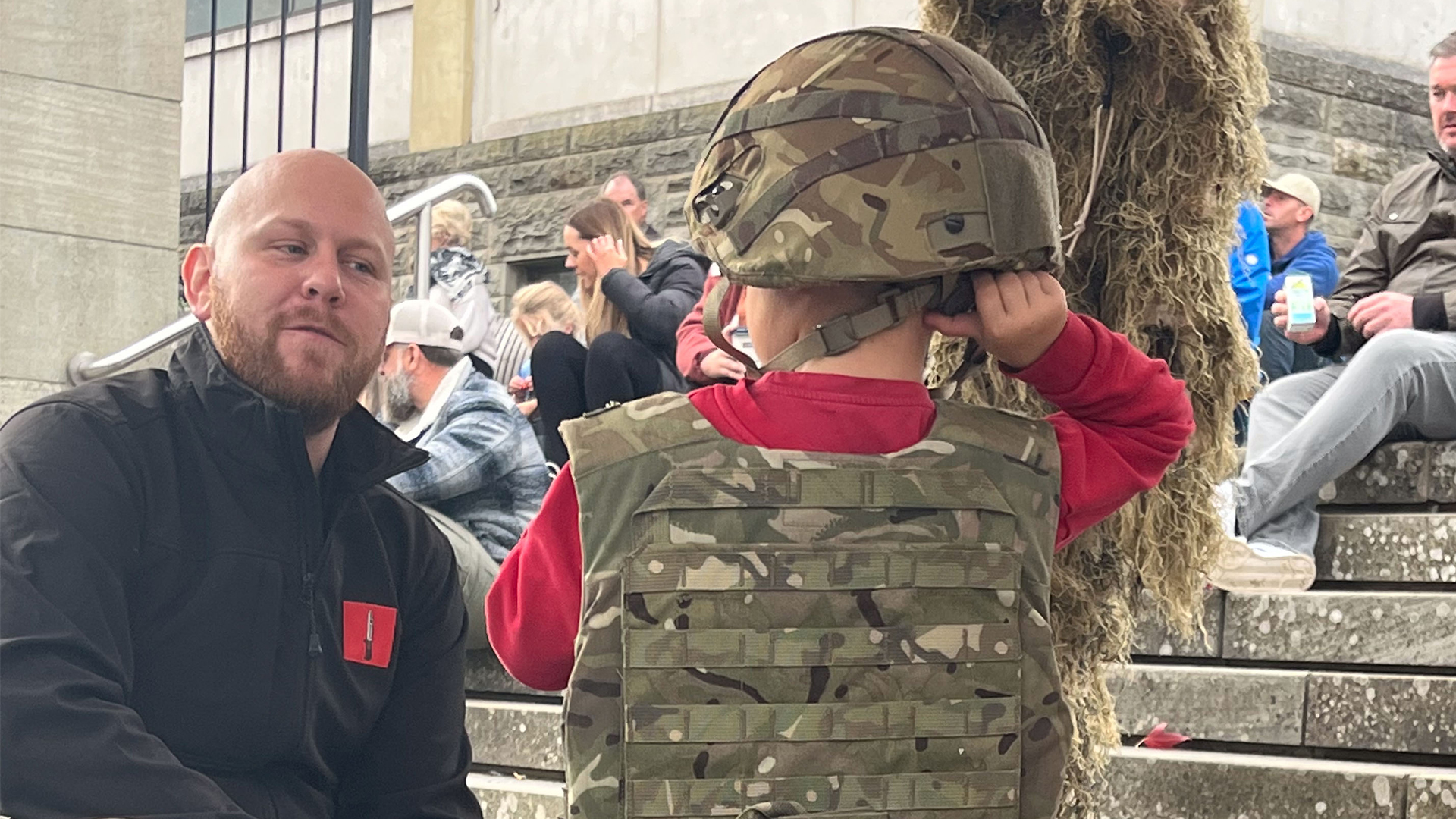 A would-be infanteer tries on a helmet and plate carrier as the returning soldiers showed off their kit
