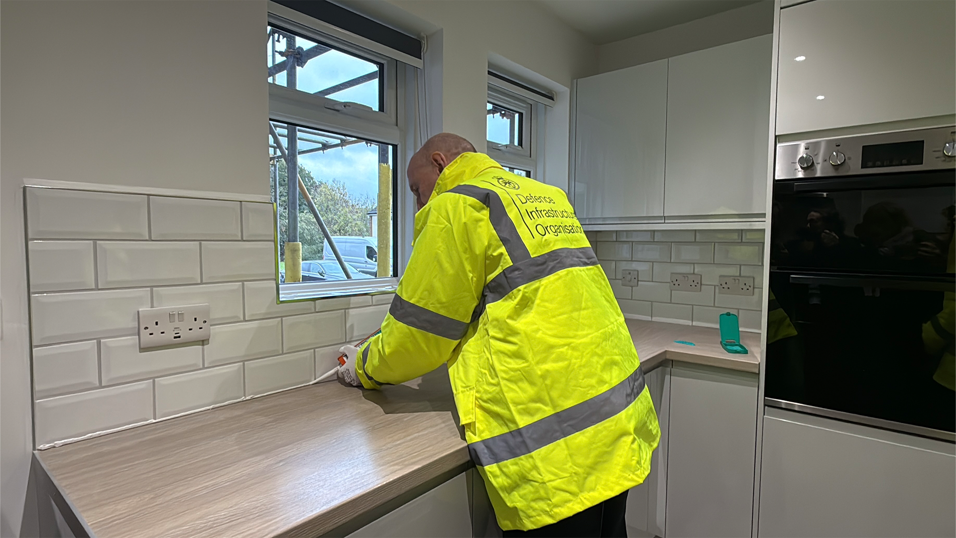 John Healey tries his hand at some caulking in new defence housing