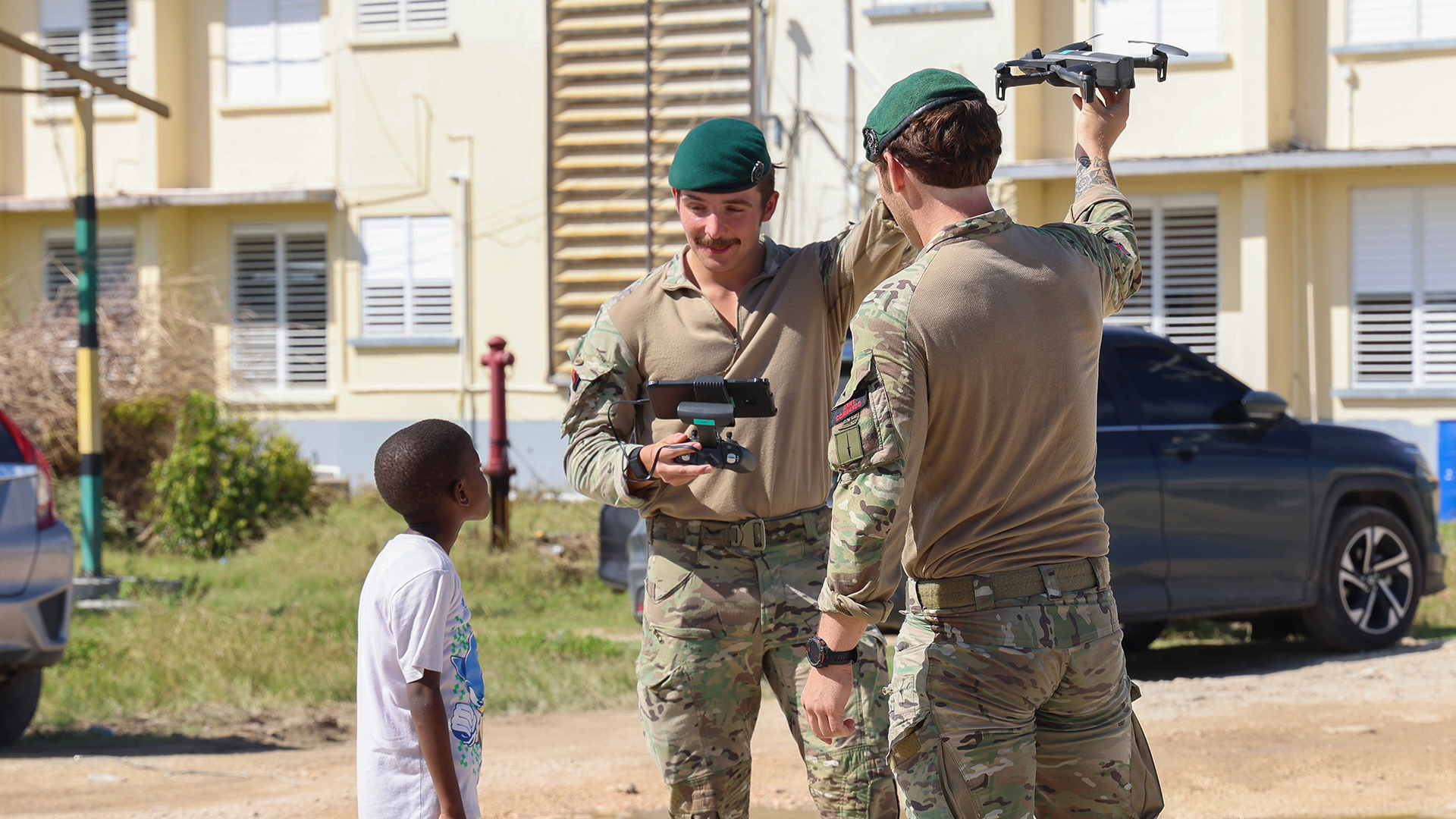Army Commandos show a local boy how a done can used to help the relief effort