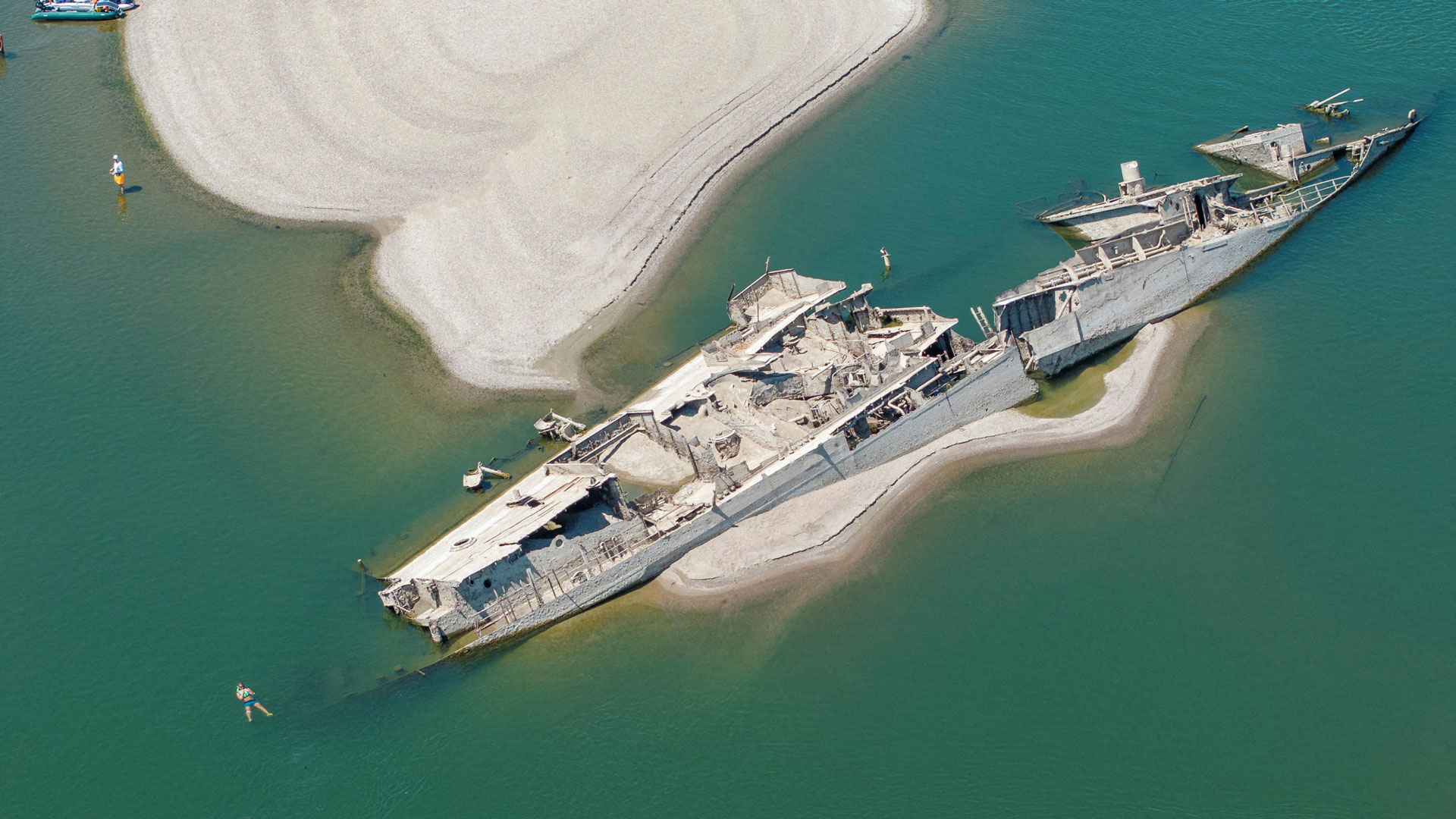 People swimming near a sunken Second World War German warship exposed due to low Danube River levels caused by drought in Prahovo, Serbia on 30 July 2026 (Picture: Reuters / Djordje Kojadinovic)