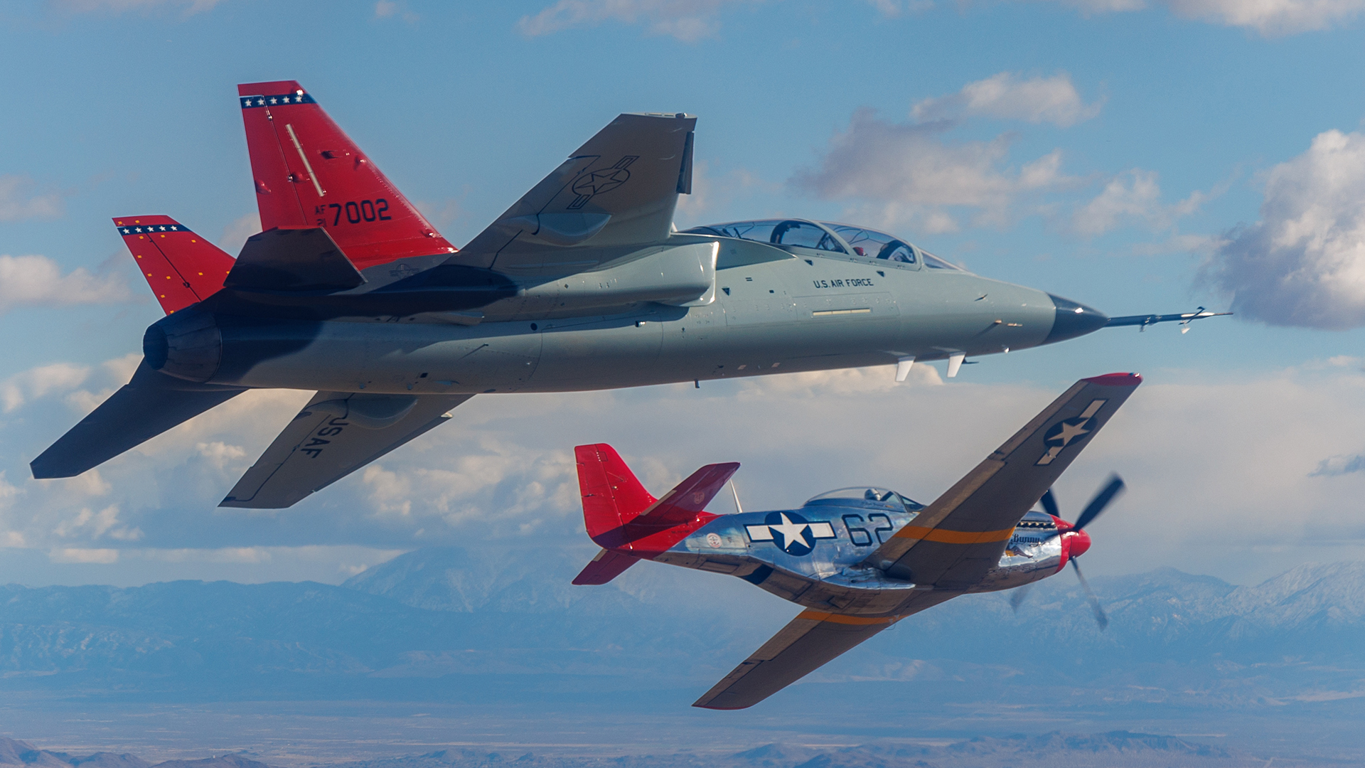 A T-7A Red Hawk flies with a P-51D Mustang painted as an aircraft operated by the Tuskegee Airmen in WW2