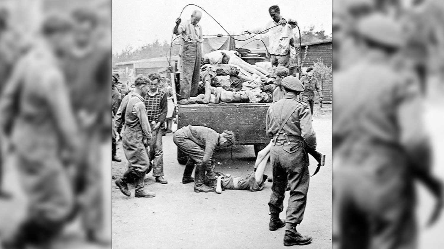 A British soldier guards SS members as they collect the dead at Belsen after its liberation in April 1945