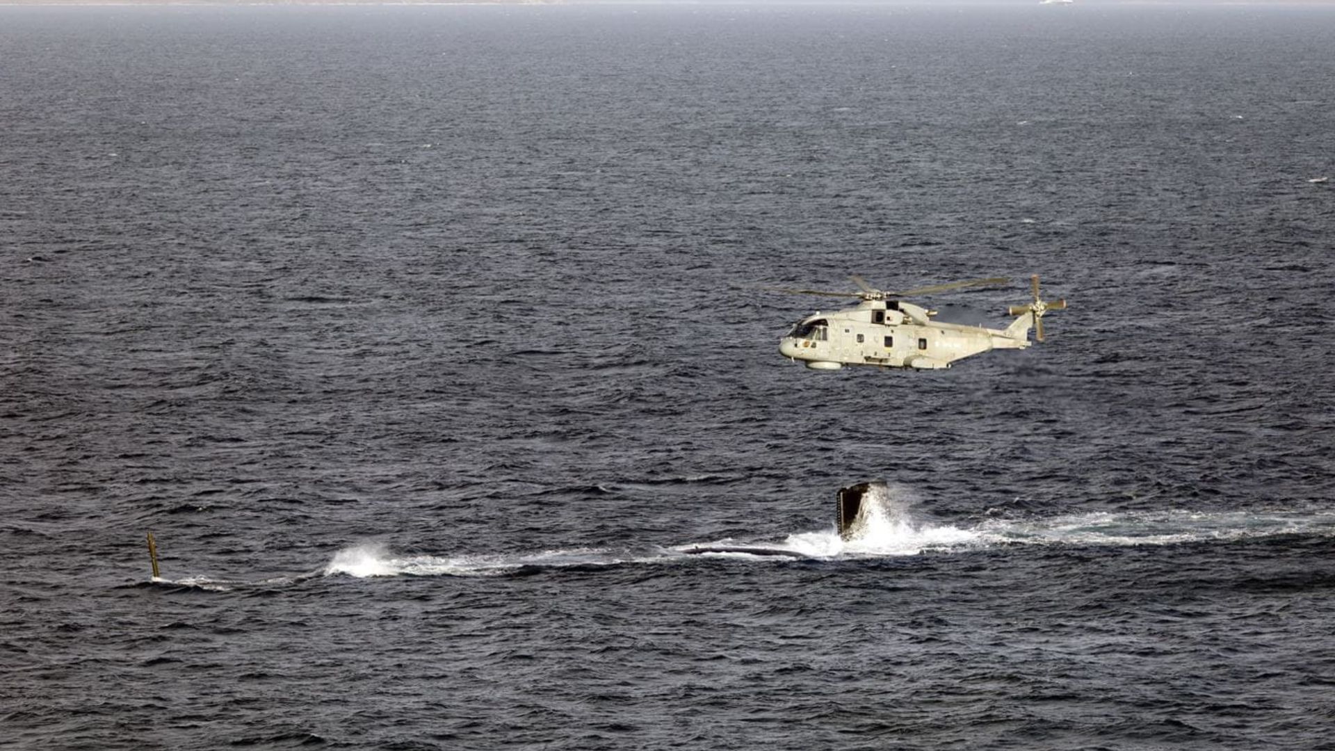 A Merlin Mk2 helicopter flies over HMS Agamemnon's tail fin as she conducts diving trials (Picture: Royal Navy)