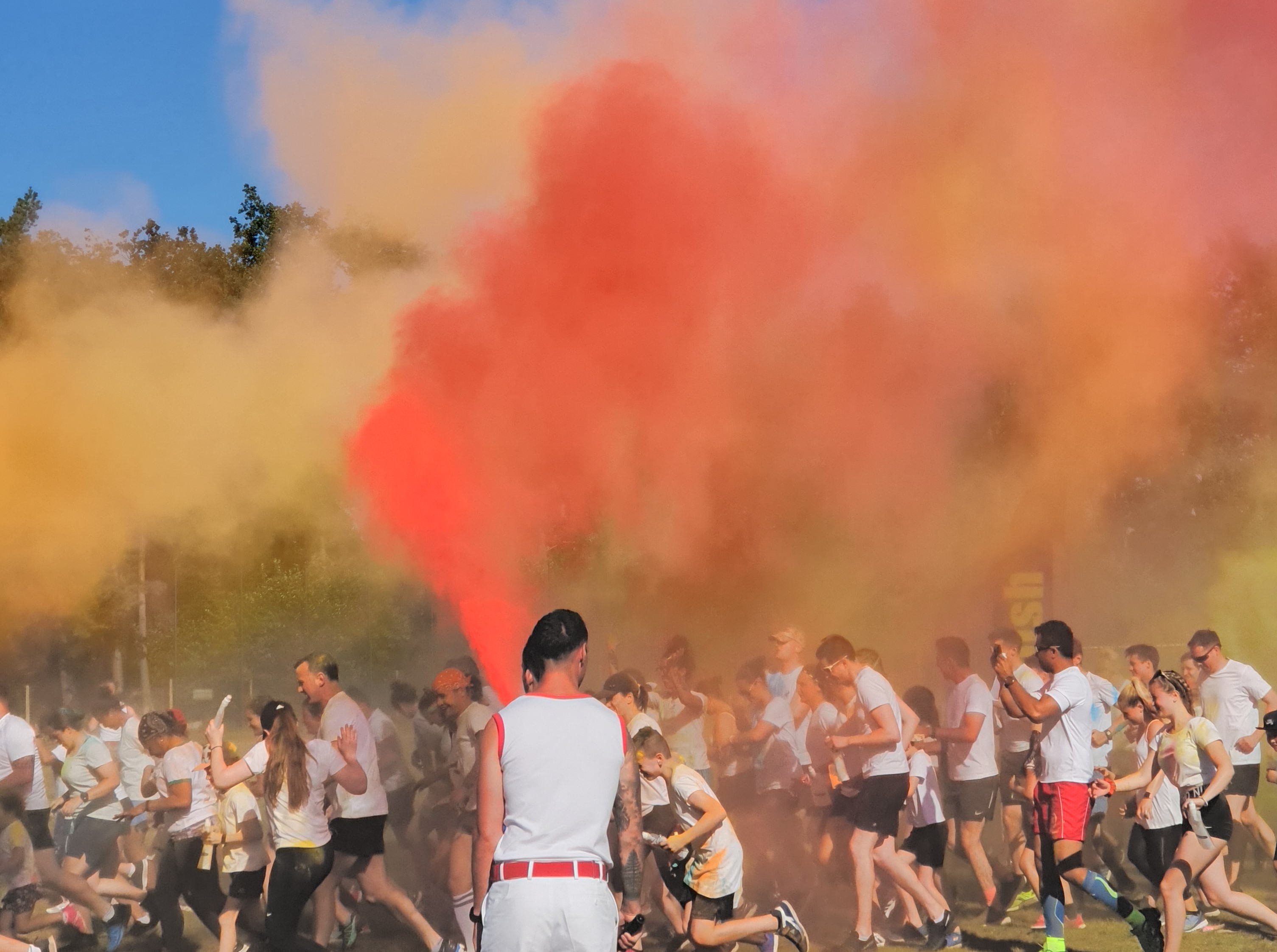 Runners starting off the colour run at Depsey Barracks, running through a haze of orange, pink and yellow paint