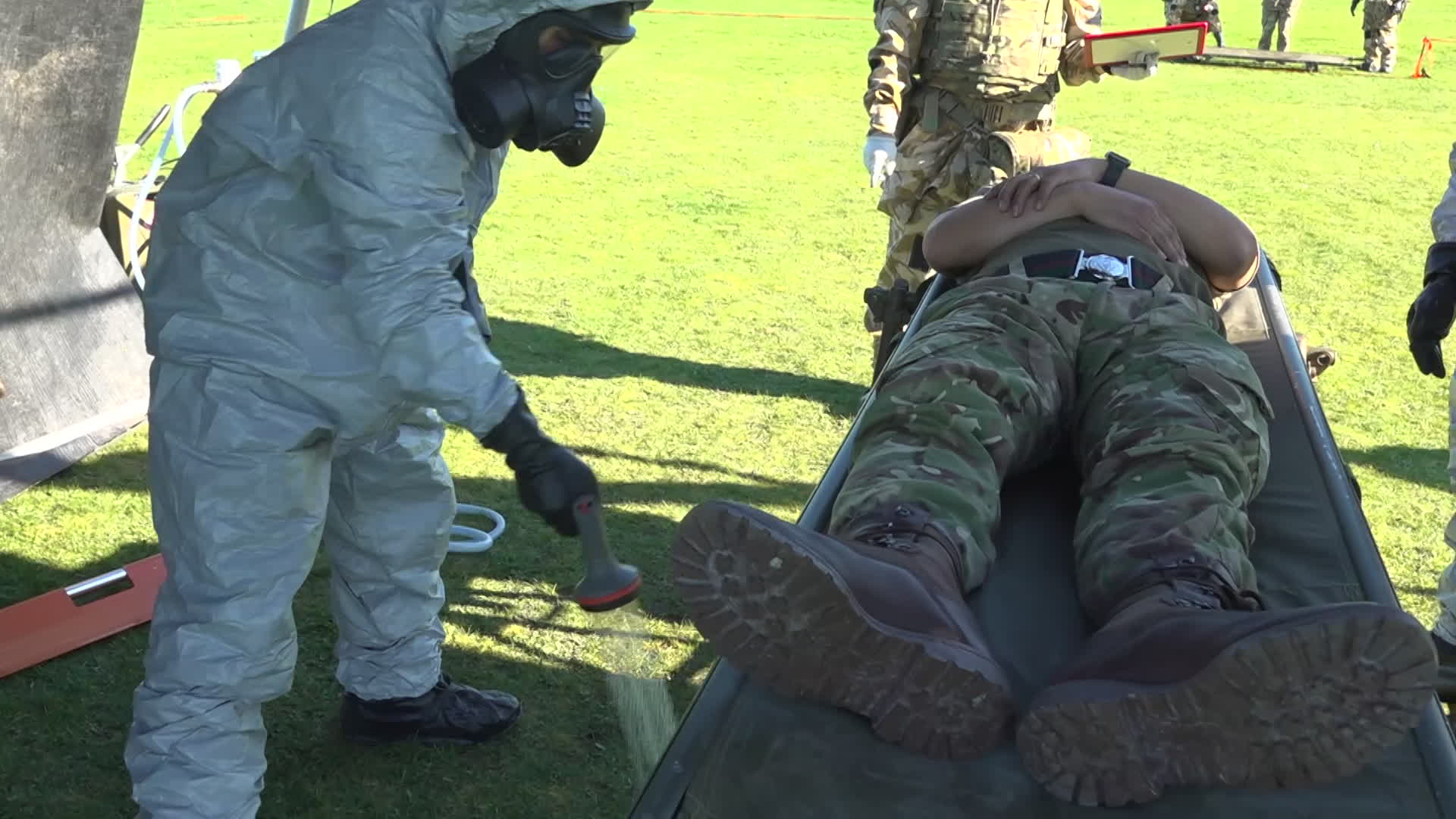 Tyvek suits are worn over the top to keep the soldiers' protective clothing dry when washing down a contaminated casualty