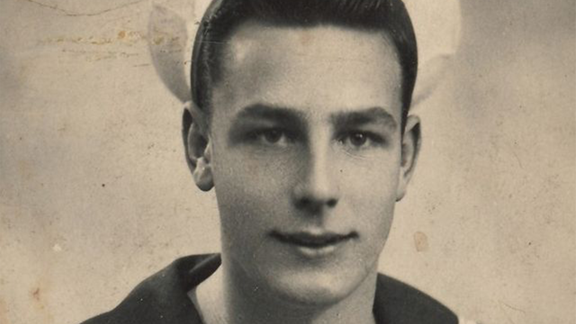 Black and white photograph of young D-Day Veteran John Dennet in sailor's uniform