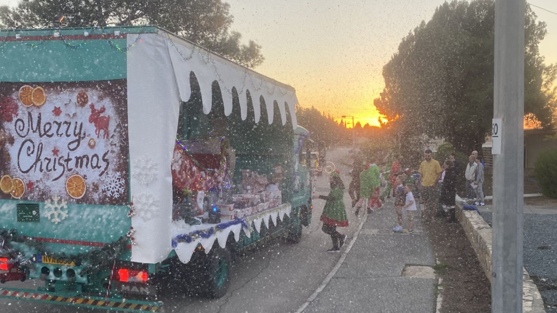 Children cheered as Santa drove past, trailing a flurry of 'snow'