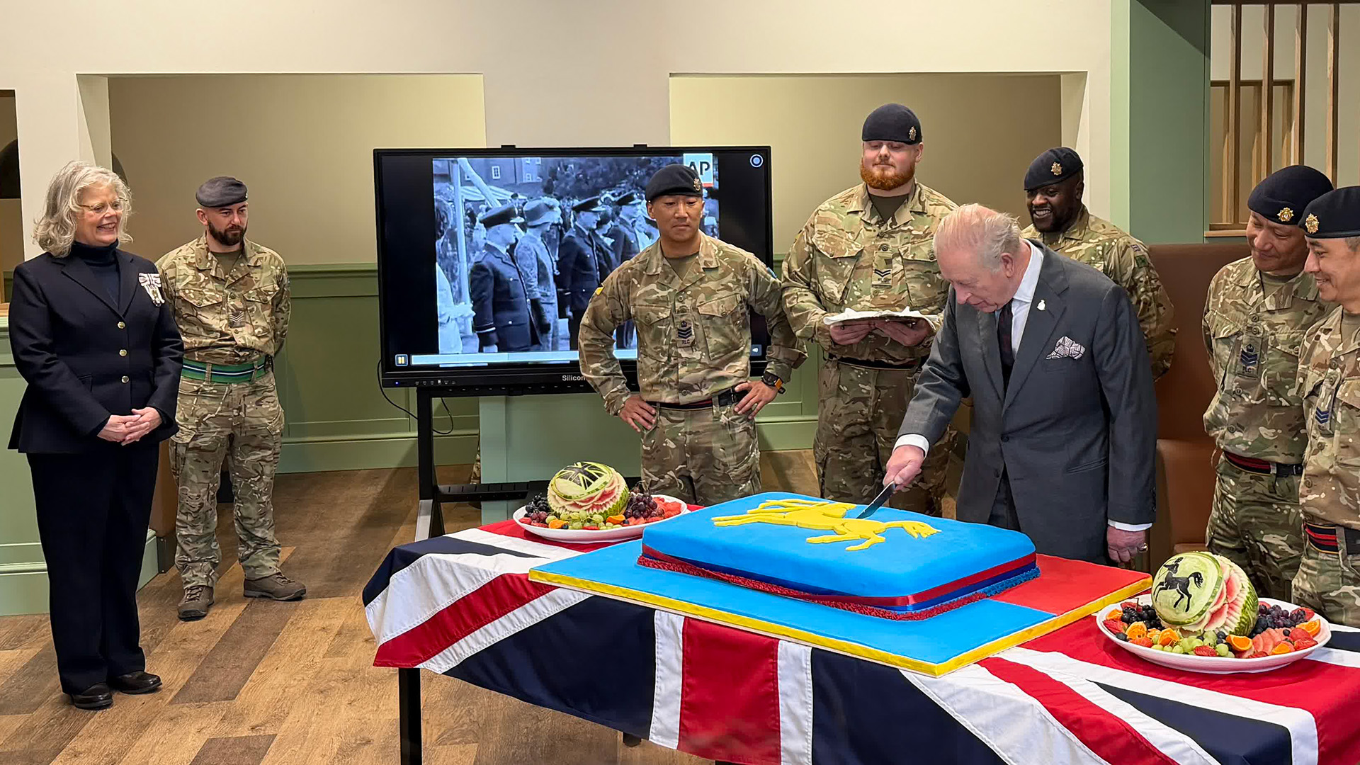 The King cuts a large blue sponge cake to mark the official opening of the Junior Ranks' Restaurant
