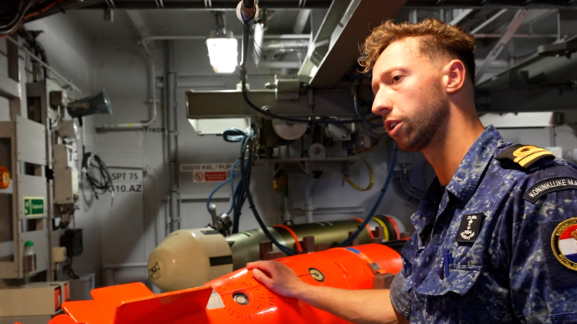 A Dutch naval officer shows one of the orange training torpedoes that help the crew perfect their defensive operations