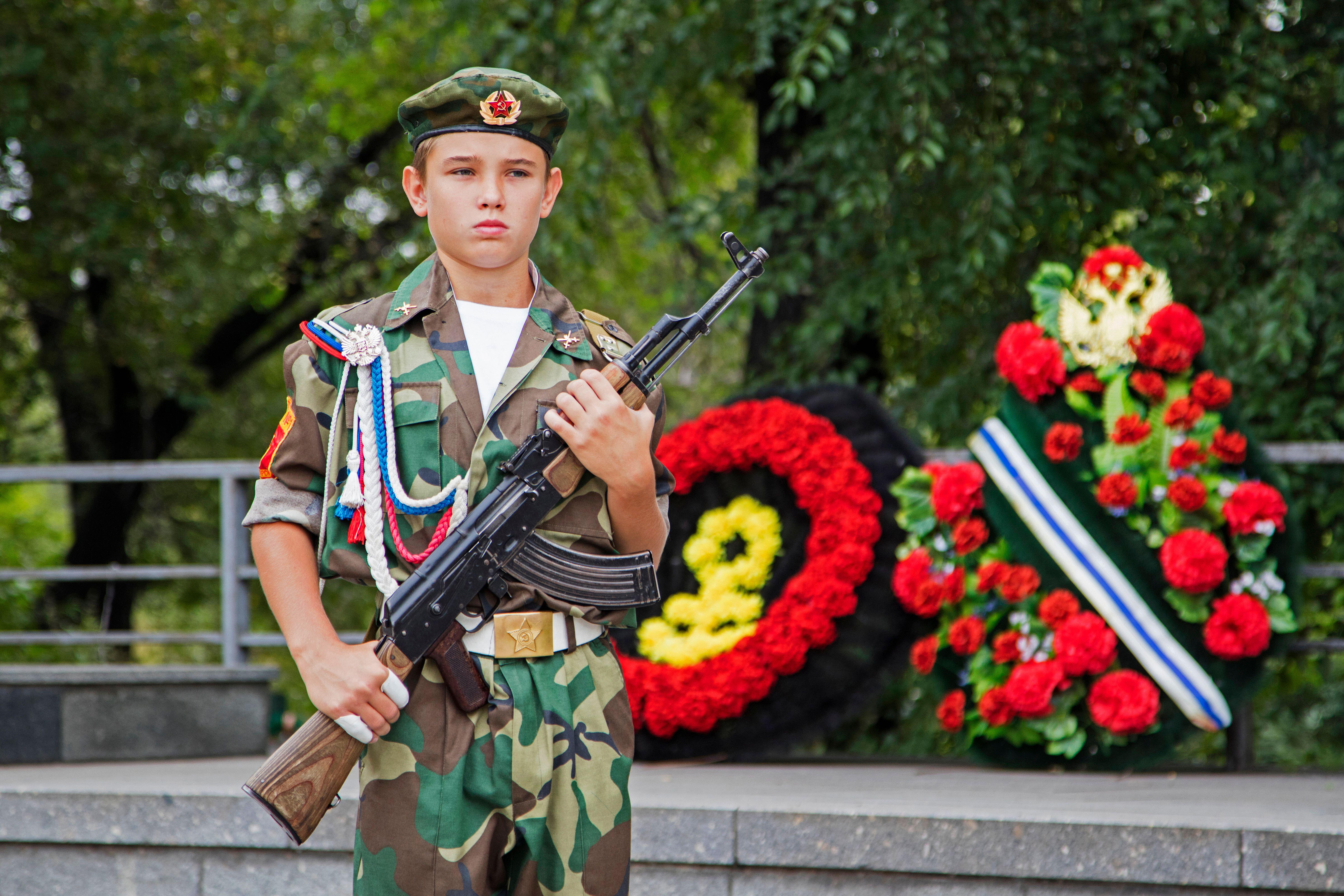 Russian boy in battledress posing with AK-47 Kalashnikov in the city Krasnojarsk, Krasnoyarsk Krai, Siberia, Russia