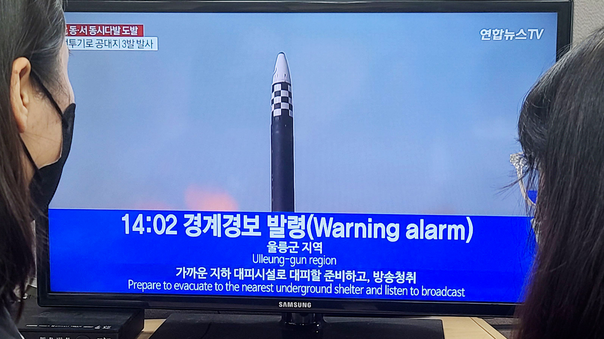 People watch the news on the lifting of an air raid alarm as of 2 p.m. at an office in Seoul after North Korea fired around 10 missiles
