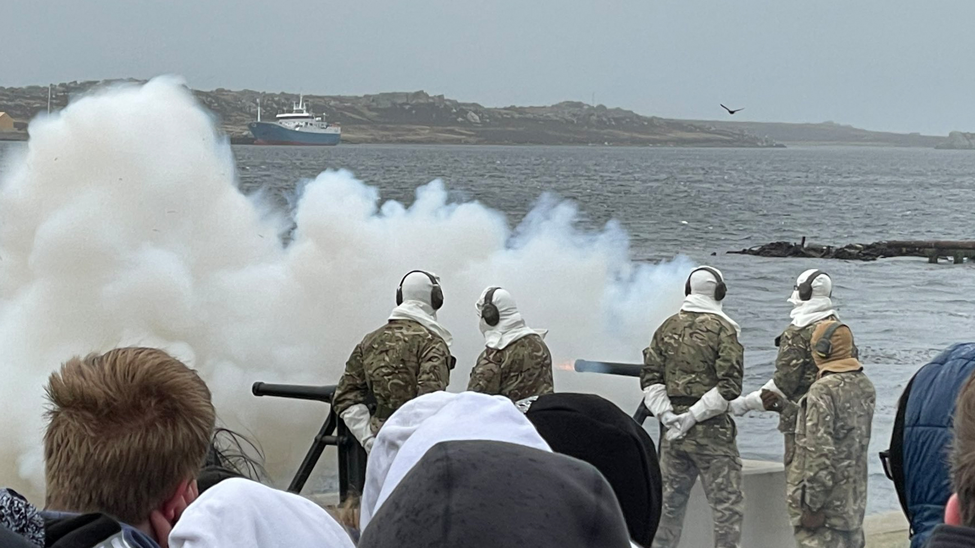 After the detonation of the blank rounds, a large plume of smoke forms around the guns