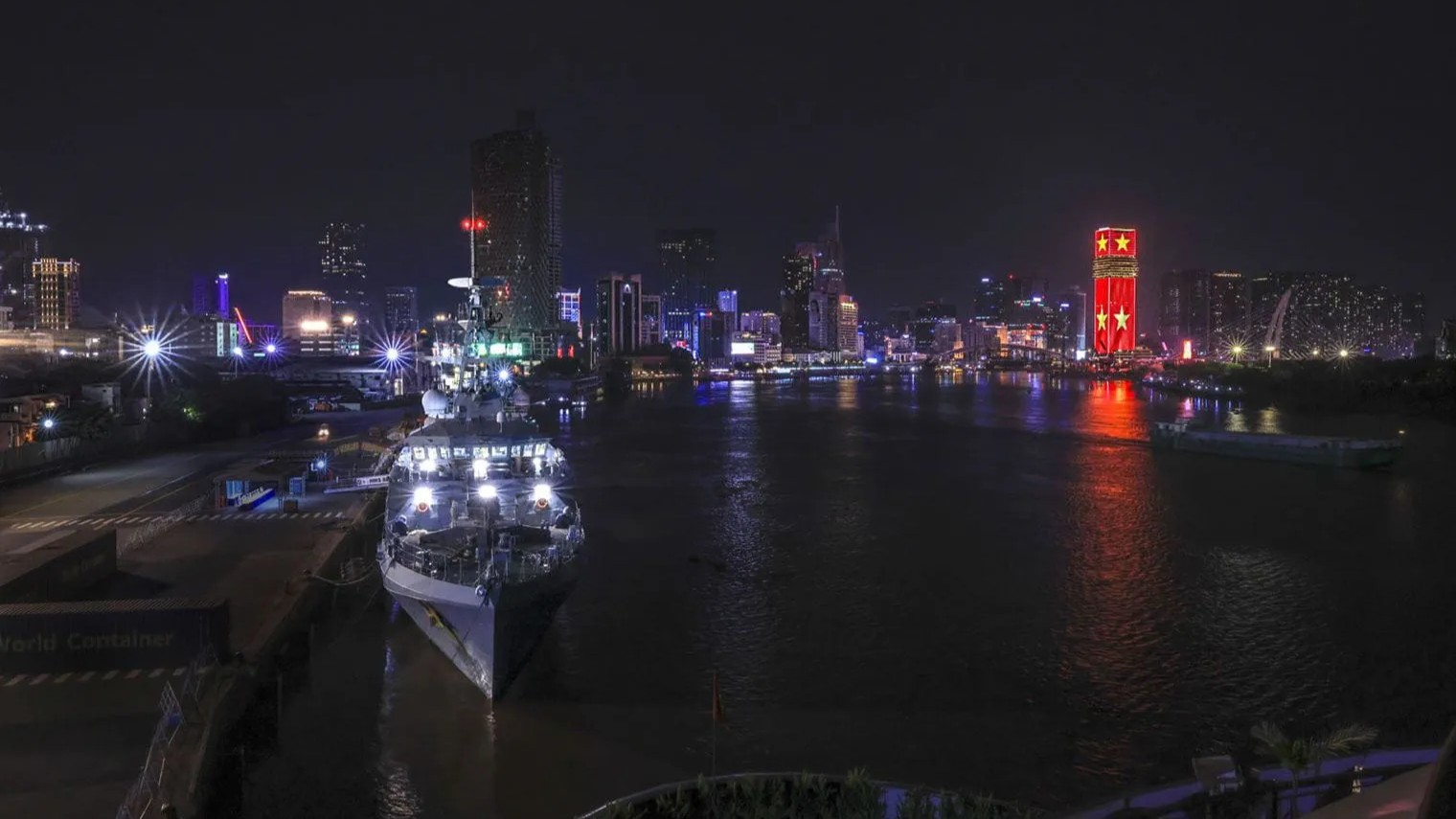 HMS Spey lit up at Saigon Port with the skyline of Ho Chi Minh City in the background pic MOD
