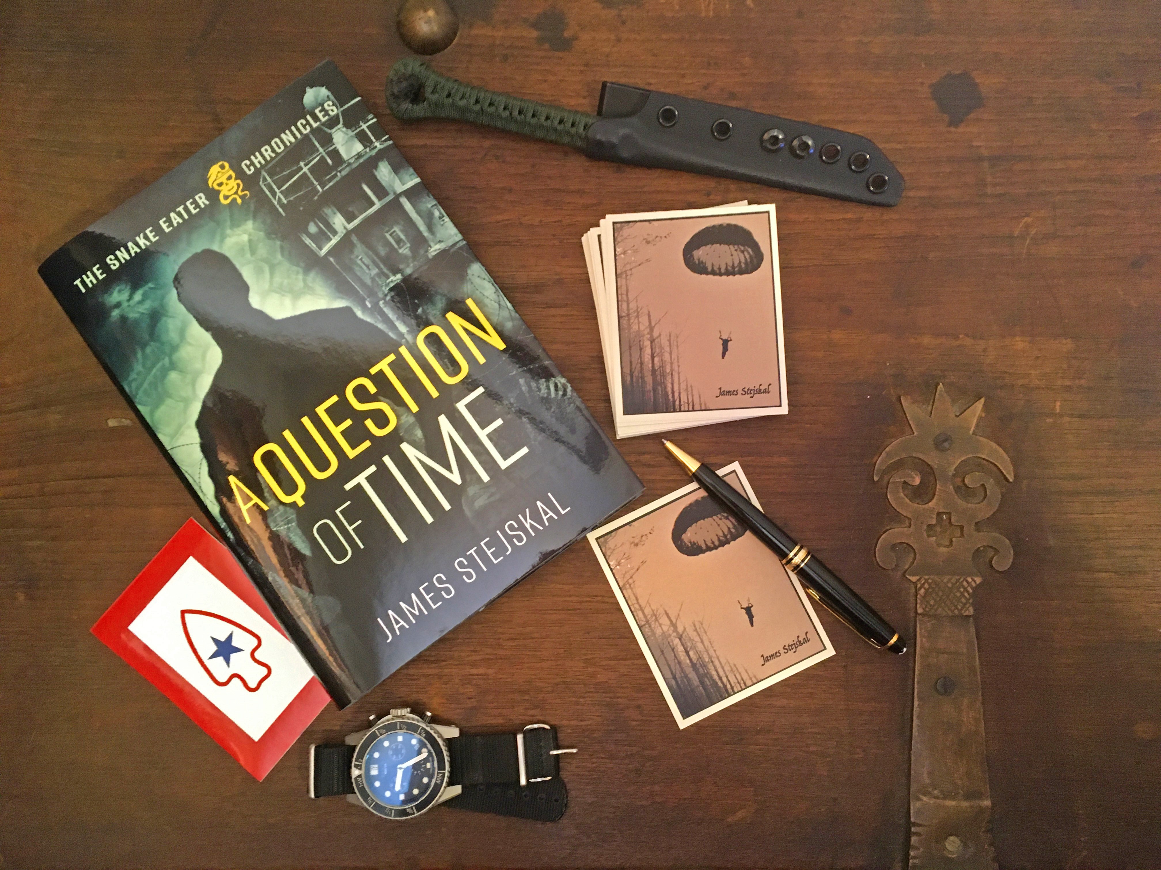 Desk with a book entitled 'A Question of Time', some cards, a watch and other items on