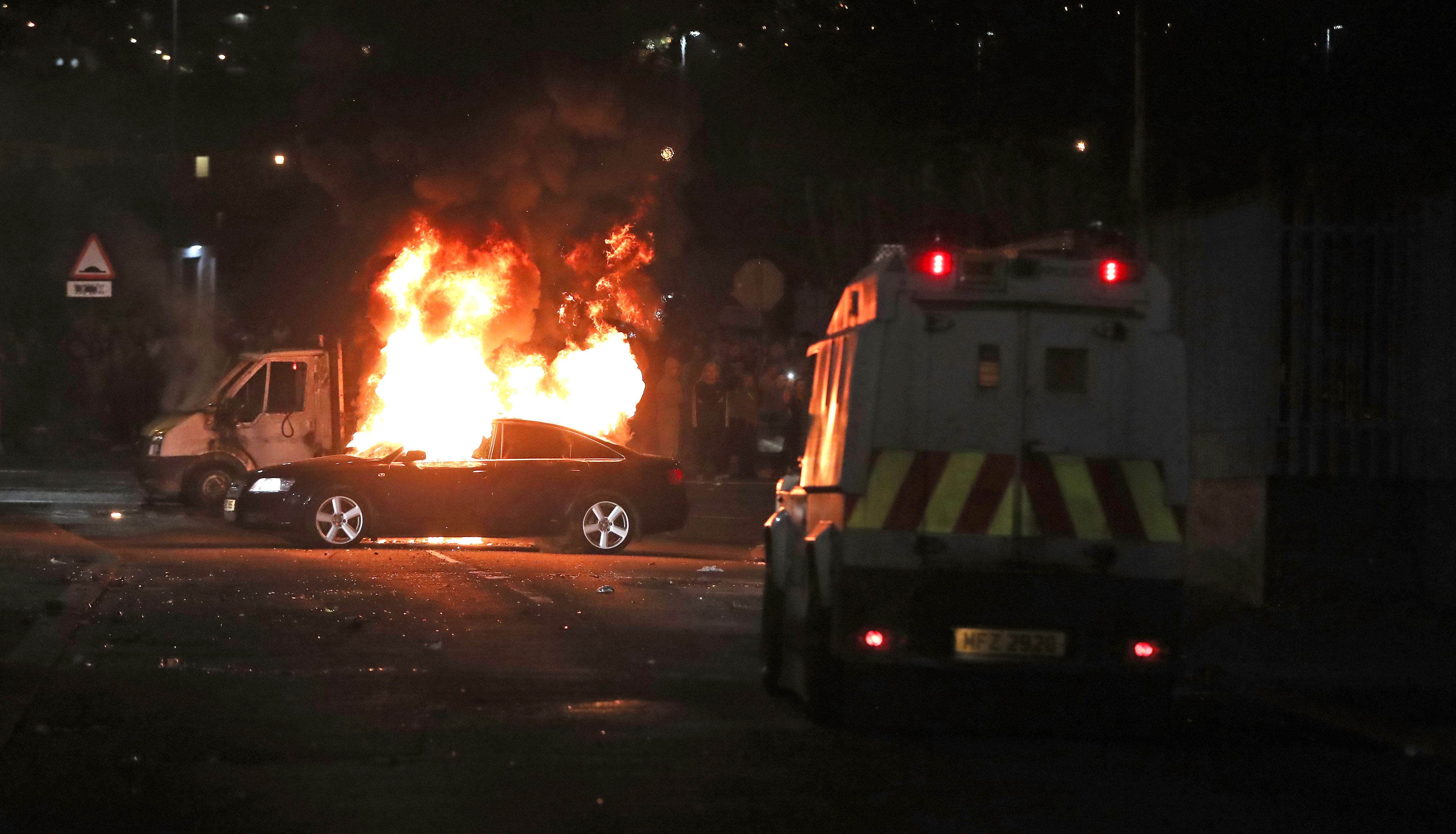 A burning car in Creggan, Londonderry, after petrol bombs were thrown at police during riots (Picture: PA).