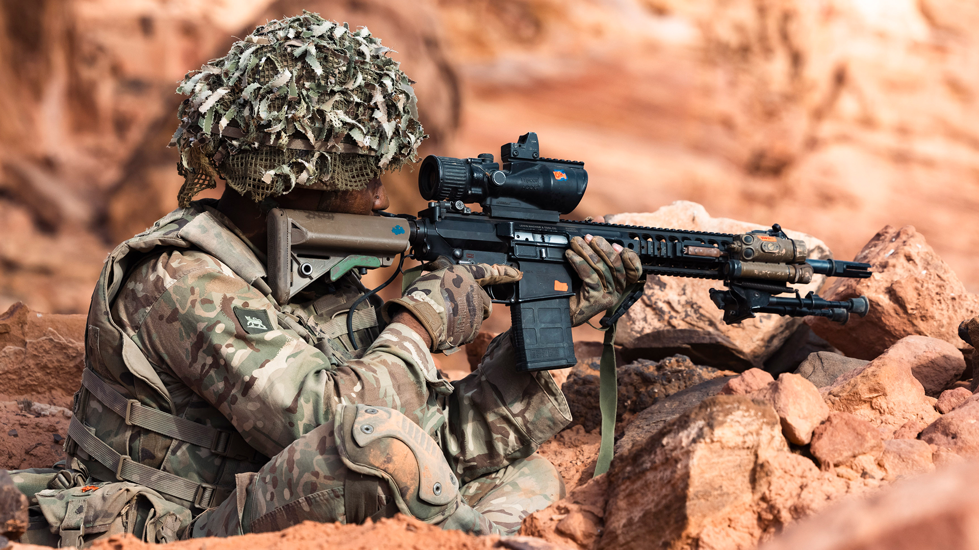 A designated marksman aims his Sharpshooter rifle from the cross-legged sitting stance
