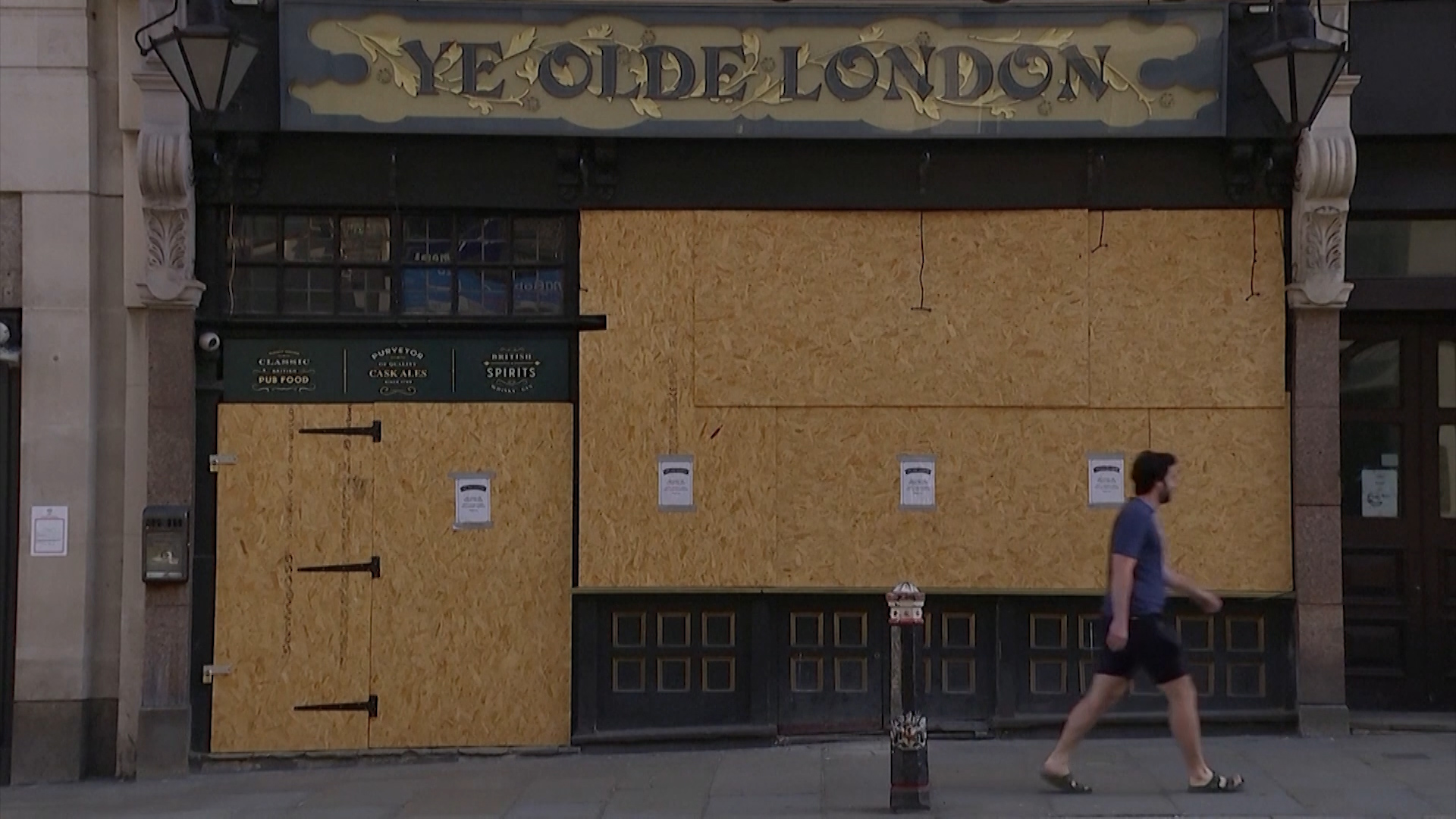 A man walks past a boarded up pub in London amid the coronavirus lockdown.