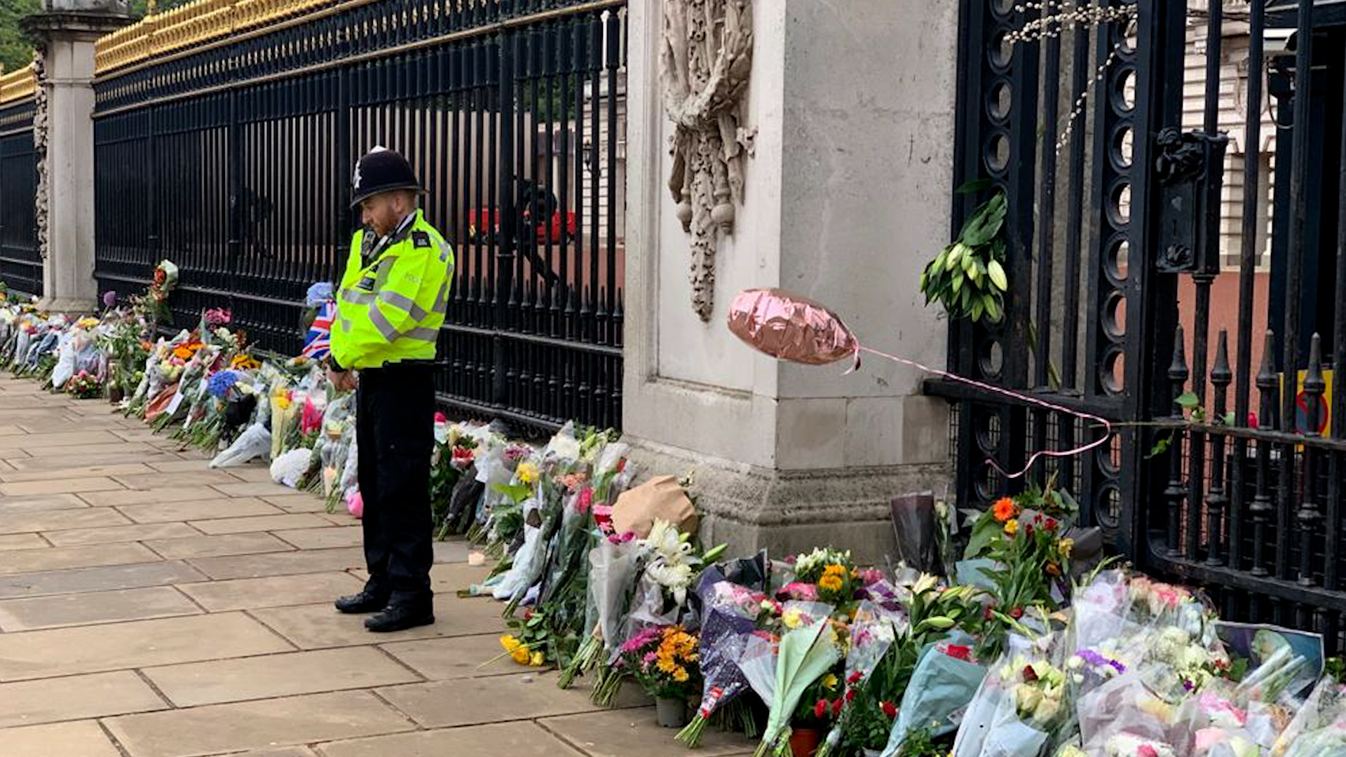 A policeman surrounded by flowers laid outside Buckingham Palace by those mourning the death of Queen Elizabeth II