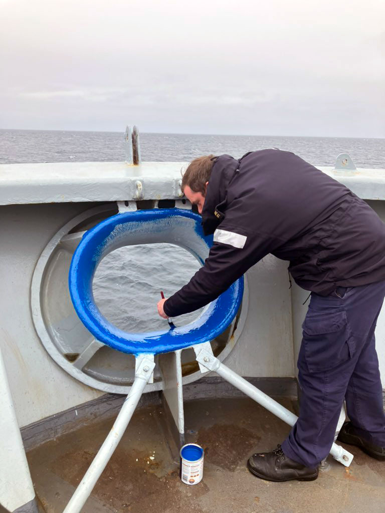 A sailor gives Enterprise's bull ring on the bow a 'blue nose' on entering the Arctic