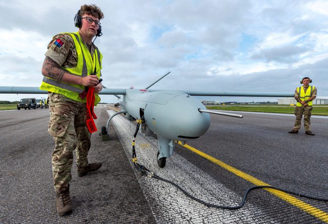 A soldier from 47 Regiment, Royal Artillery, removes safety warnings and covers from a Watchkeeper Unmanned Arial Vehicle at Lydd Airport, Kent