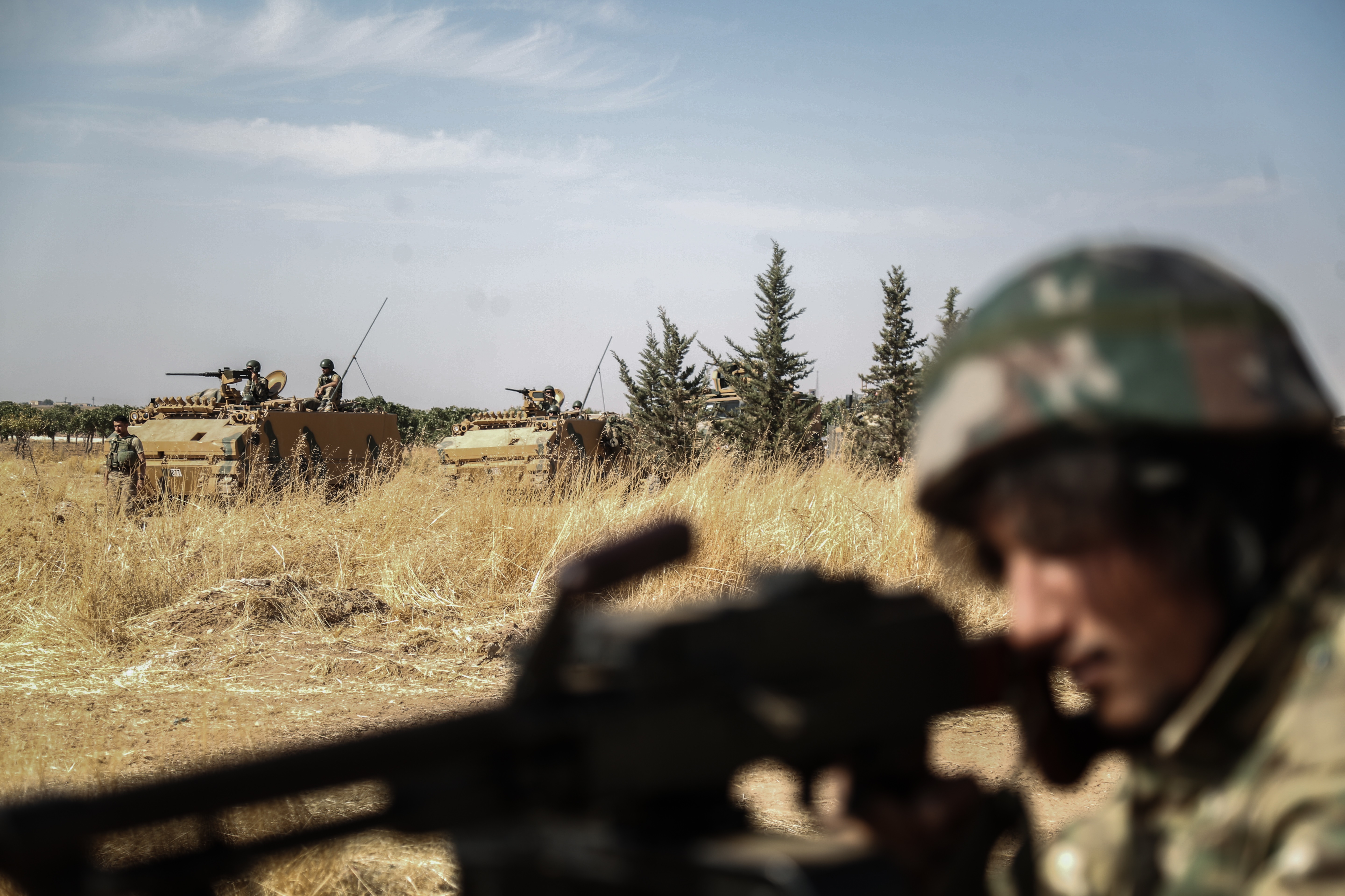A soldier of the Turkish-backed Syrian National Army is backdropped by Turkish tanks near the Syrian-Turkish border town Mabrouka (Picture: PA).