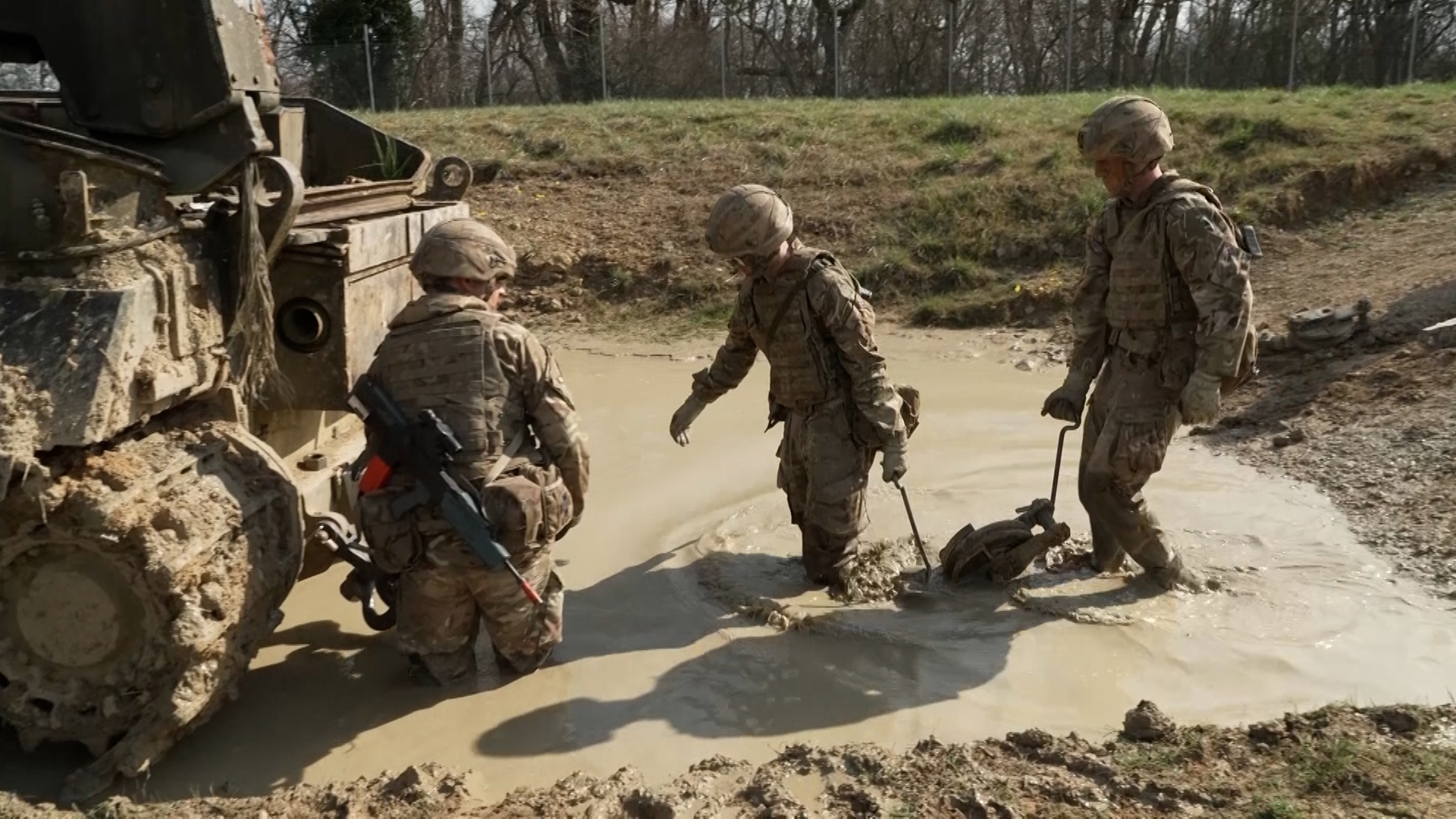 A tow cable is brought up to be attached to the bogged-down armoured vehicle