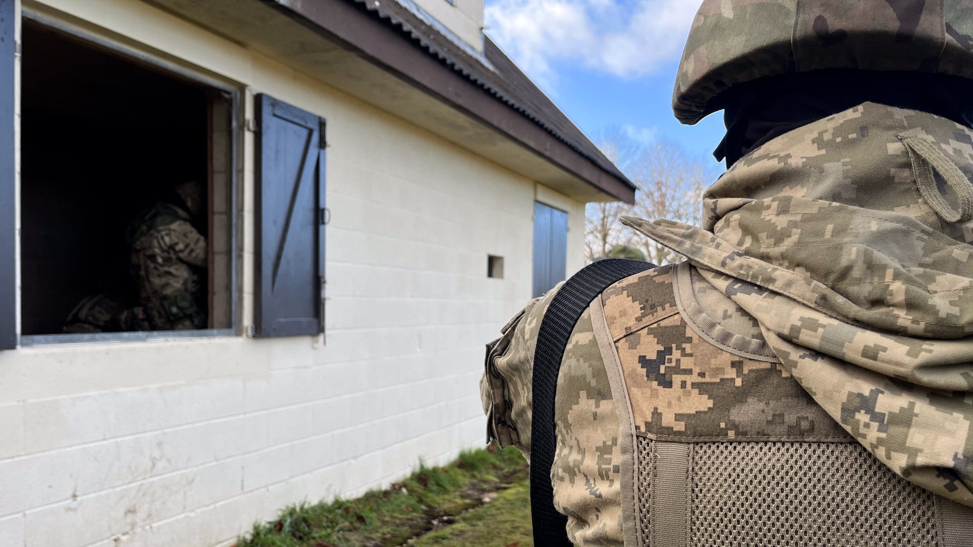 An over the shoulder close up of Ukrainian volunteers in a fake village in the UK for frontline training