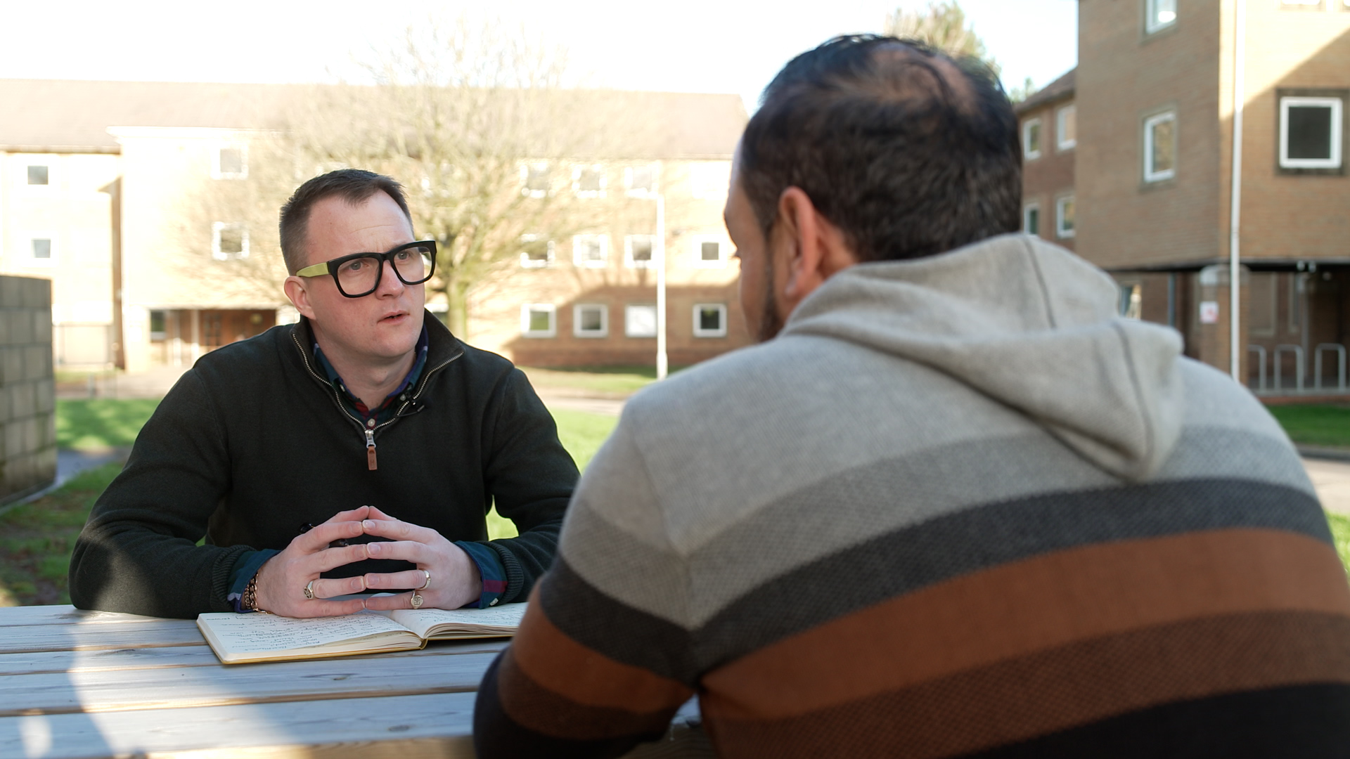 Two men talk at a table