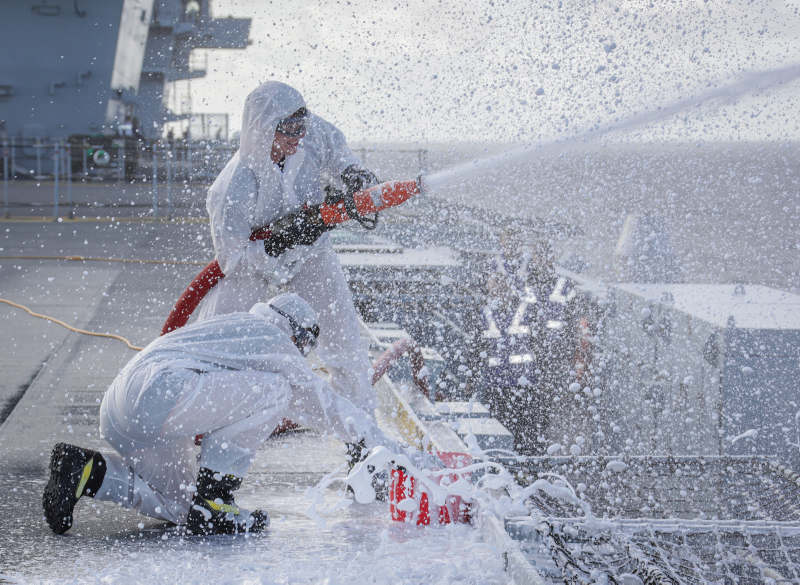 HMS Queen Elizabeth Flight deck crews testing out part of her foam firefighting capability, the tests were to establish that the foam mixture was correct and was achieved by collecting the foam from the high pressure stream into buckets.