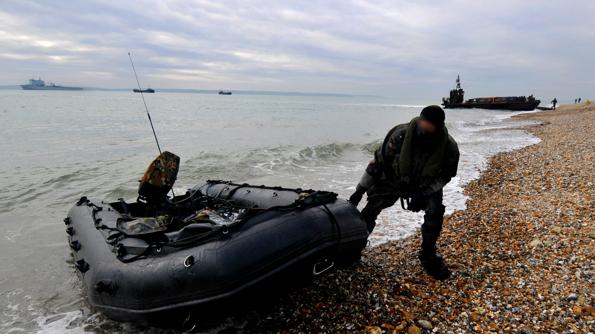 A member of the Special Boat Service (SBS) dragging a boat onto a beach