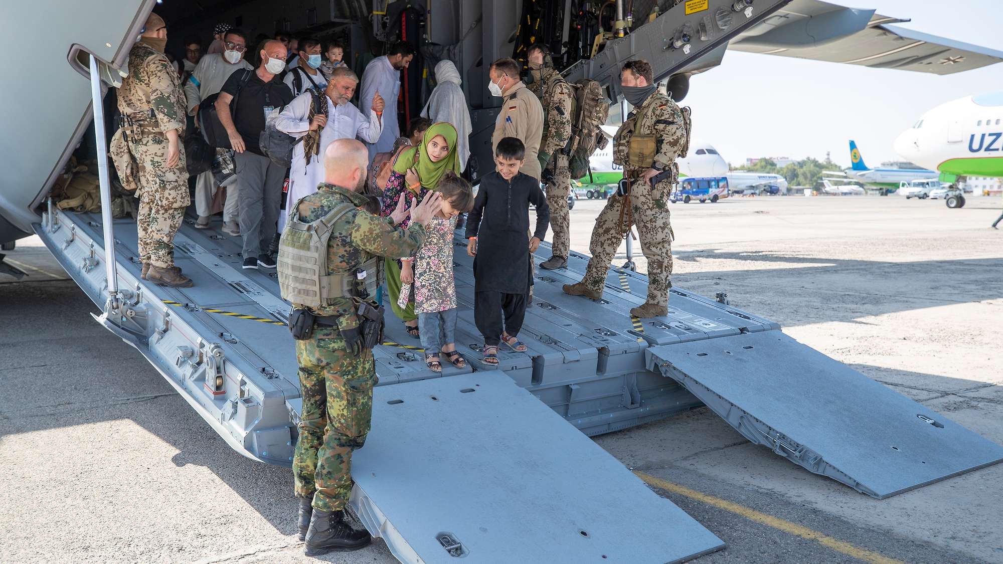 Bundeswehr soldiers escort people from Afghanistan off the plane after landing in Tashkent August 2021 CREDIT Bundeswehr Marc Tessensohn