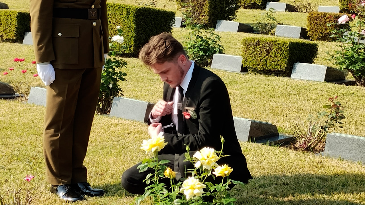 Great Nephew of Corporal Adair, Cameron Adair knelt at his Great Uncle's grave, paying his respects (Picture: Crown Copyright)