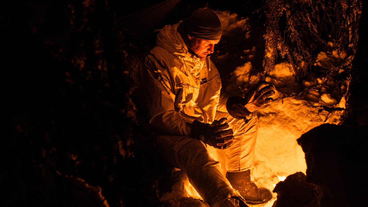 Cold weather operations training in Norway. A Norwegian instructor sits next to a fire in a survival camp built in the Norwegian forest CREDIT Nato