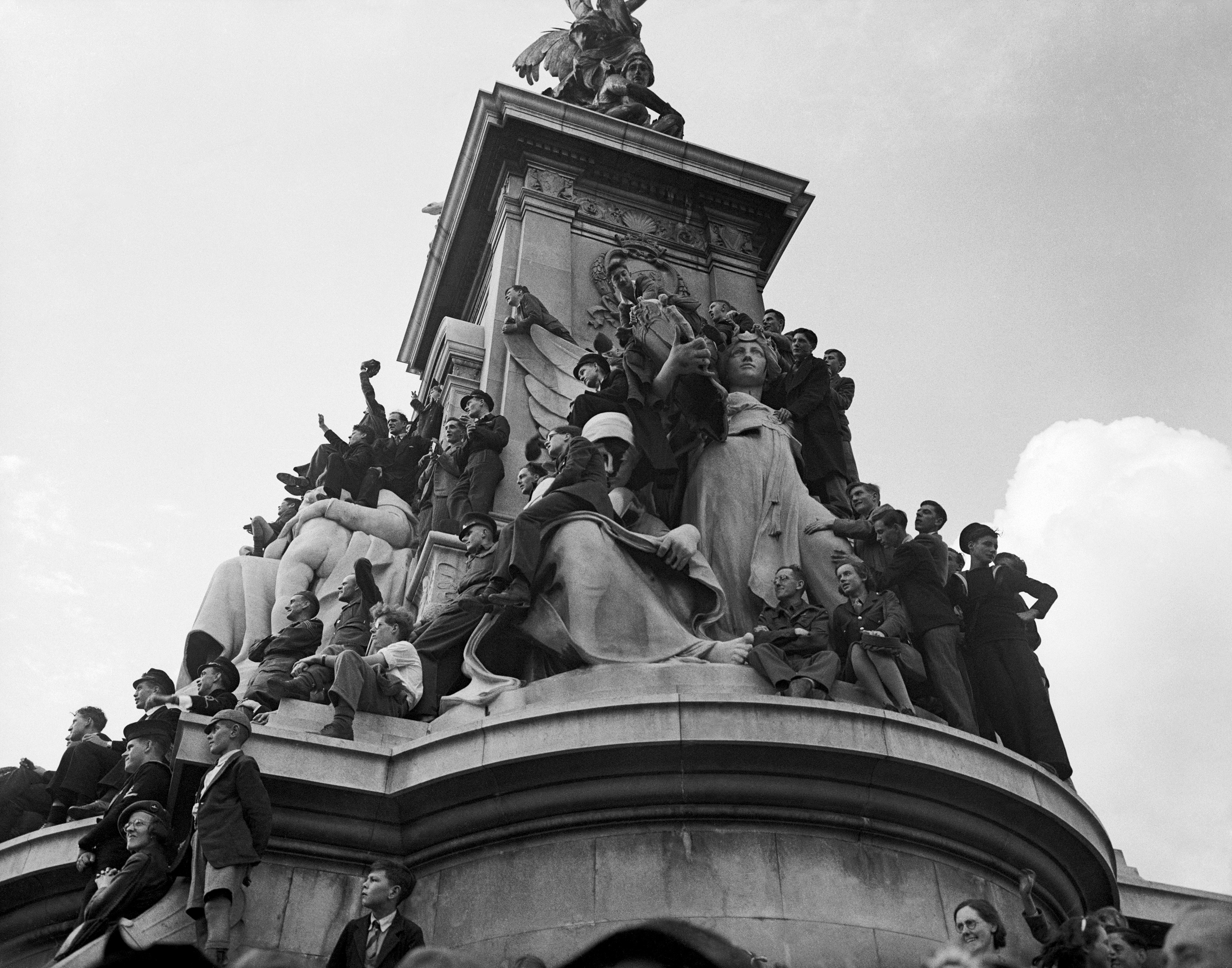 Crowds on the Victoria Memorial outside Buckingham Palace when the King and Queen took to the balcony to acknowledge the crowds on VJ Day in 1945 (Picture: PA).