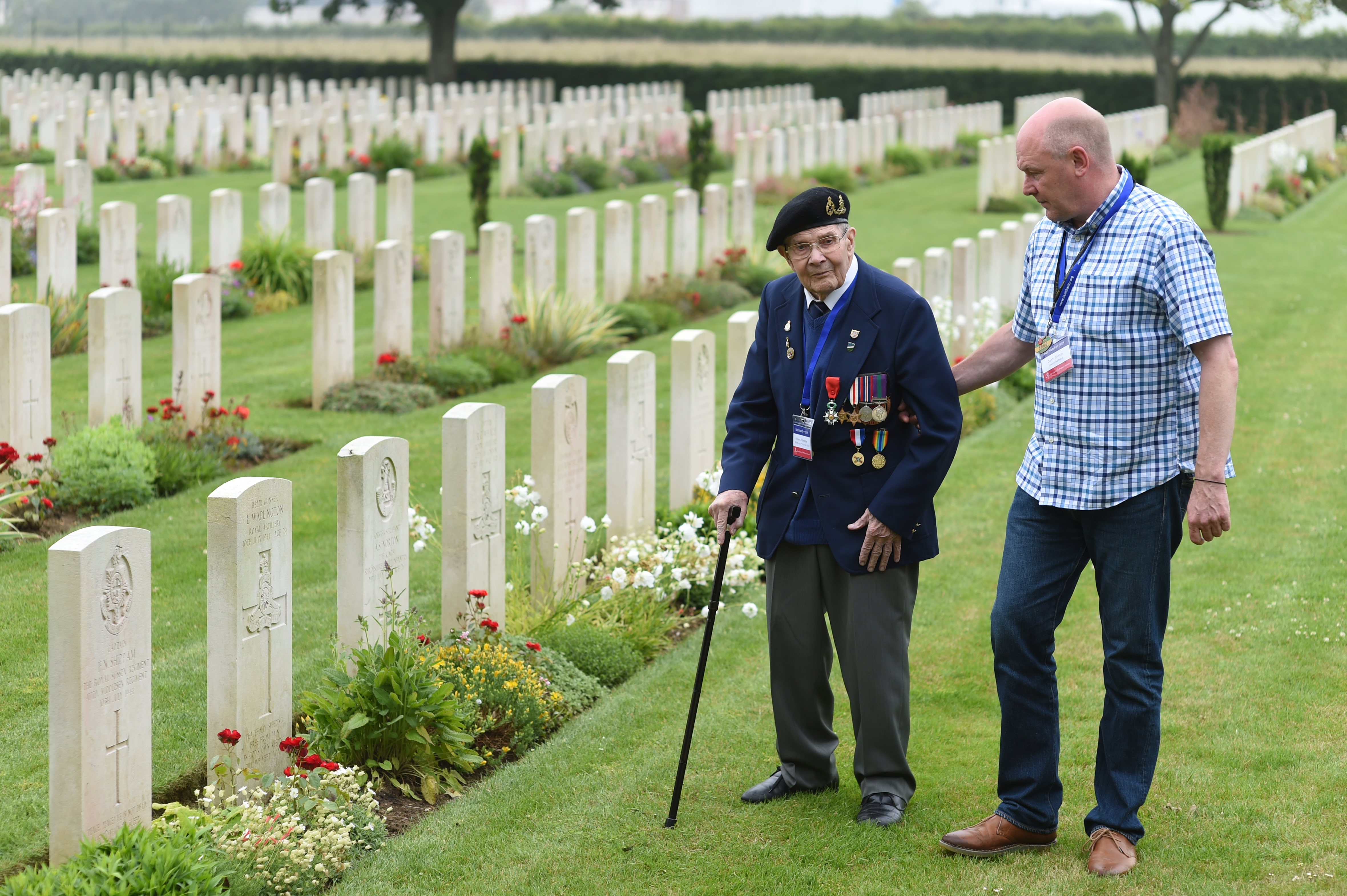 A veteran is accompanied by Taxi Charity volunteers at a CWGC site in Normandy, France. Credit: Taxi Charity