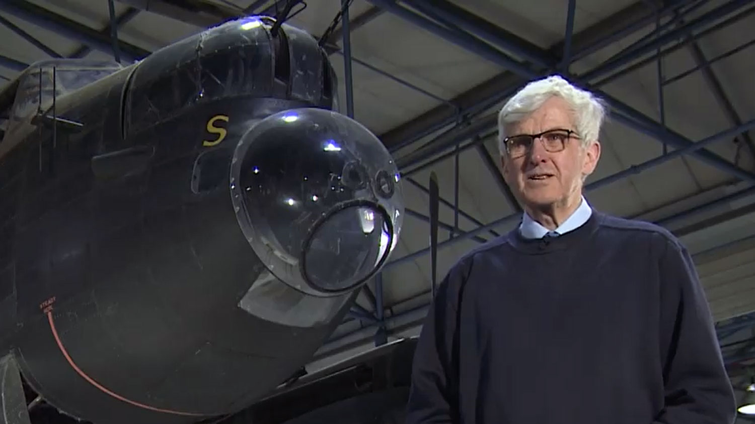 Aviation historian David Keen stands in front of an Avro Lancaster CREDIT Screengrab from BFBS footage