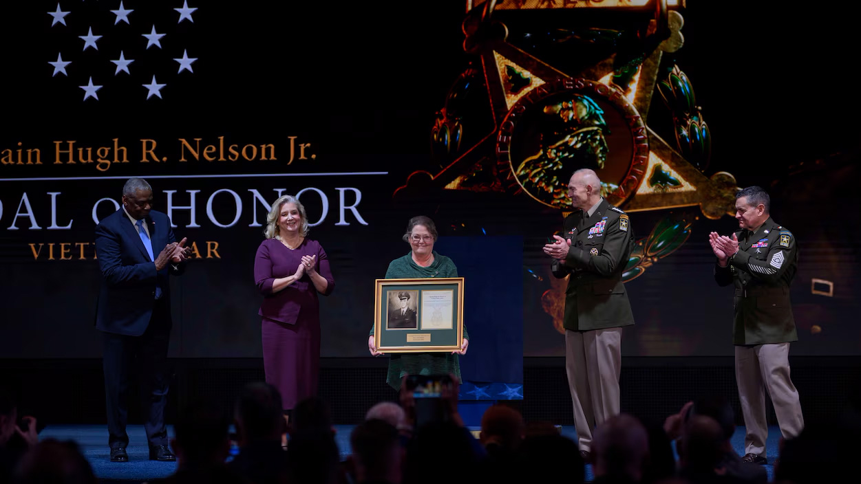 Debra Nelson McKnight holds the plaque of her father, Medal of Honor recipient Army Capt. Hugh R. Nelson Jr.