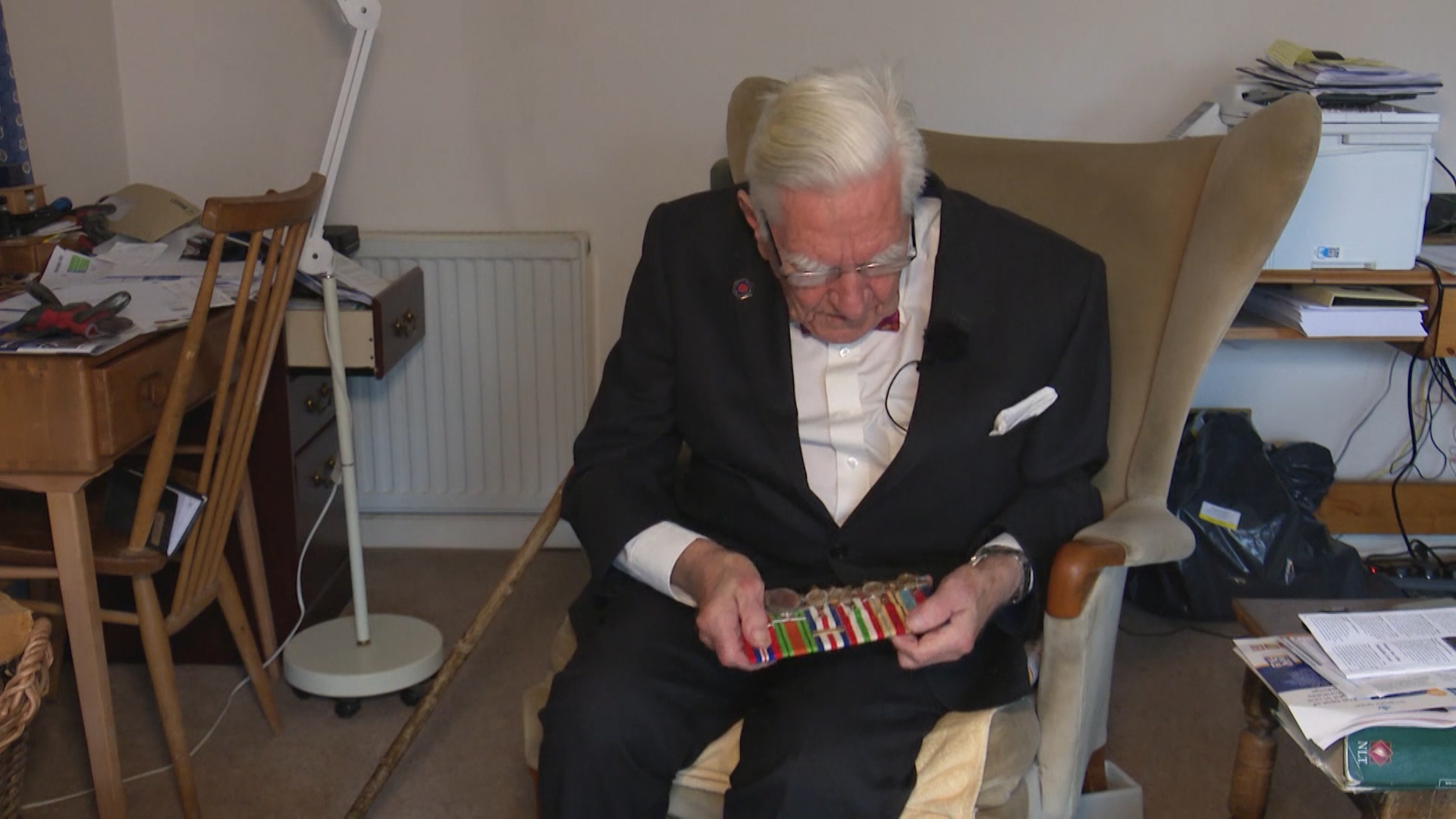 Denis Cooper looking at his military service medals.
