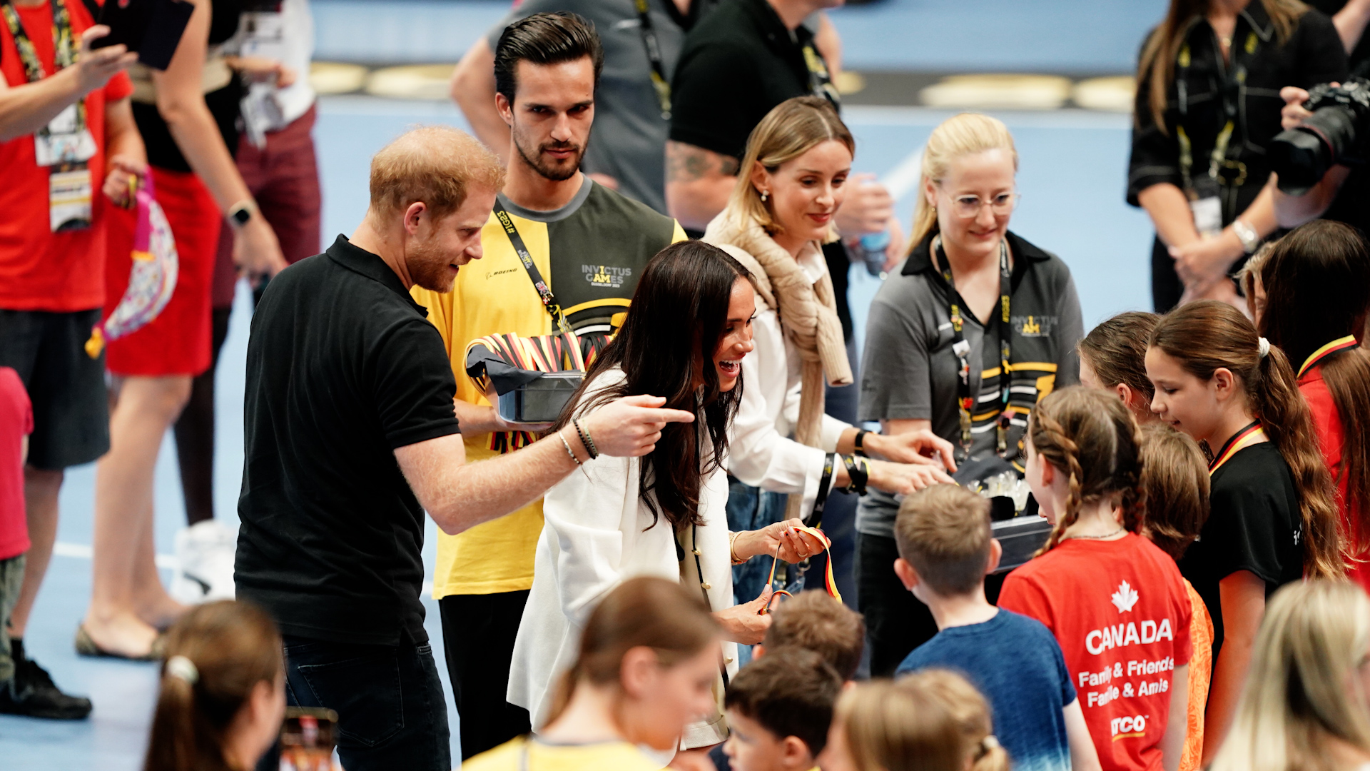 The Duke and Duchess of Sussex hand out medals to children on basketball court at the Merkur Spiel-Arena
