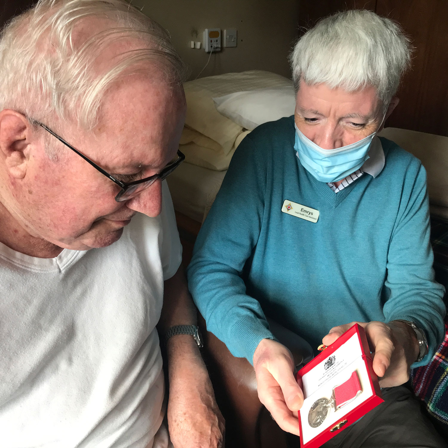 Emrys Owen shows his British Empire Medal to Royal Air Force veteran and resident Michael (Picture: Royal Star & Garter).