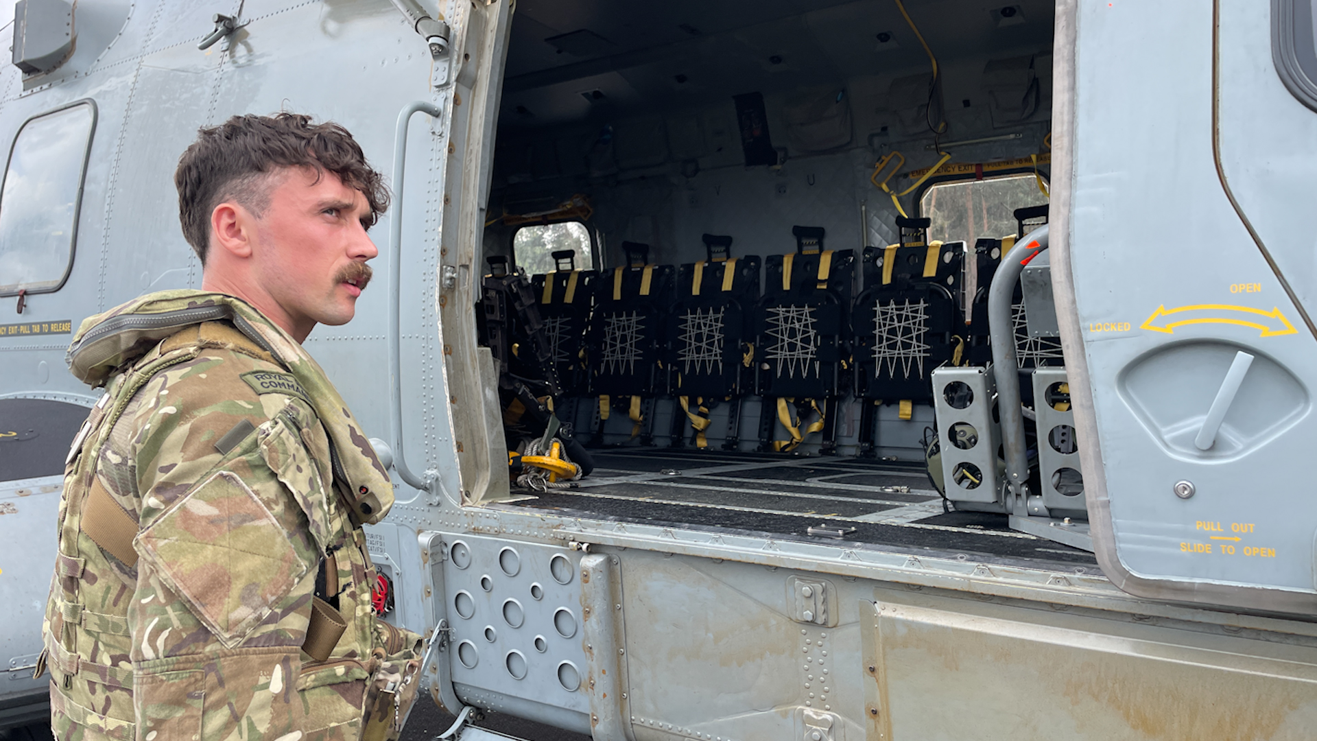 Lieutenant Oliver Wilkinson-Gray of 846 Naval Air Squadron next to Merlin helicopter