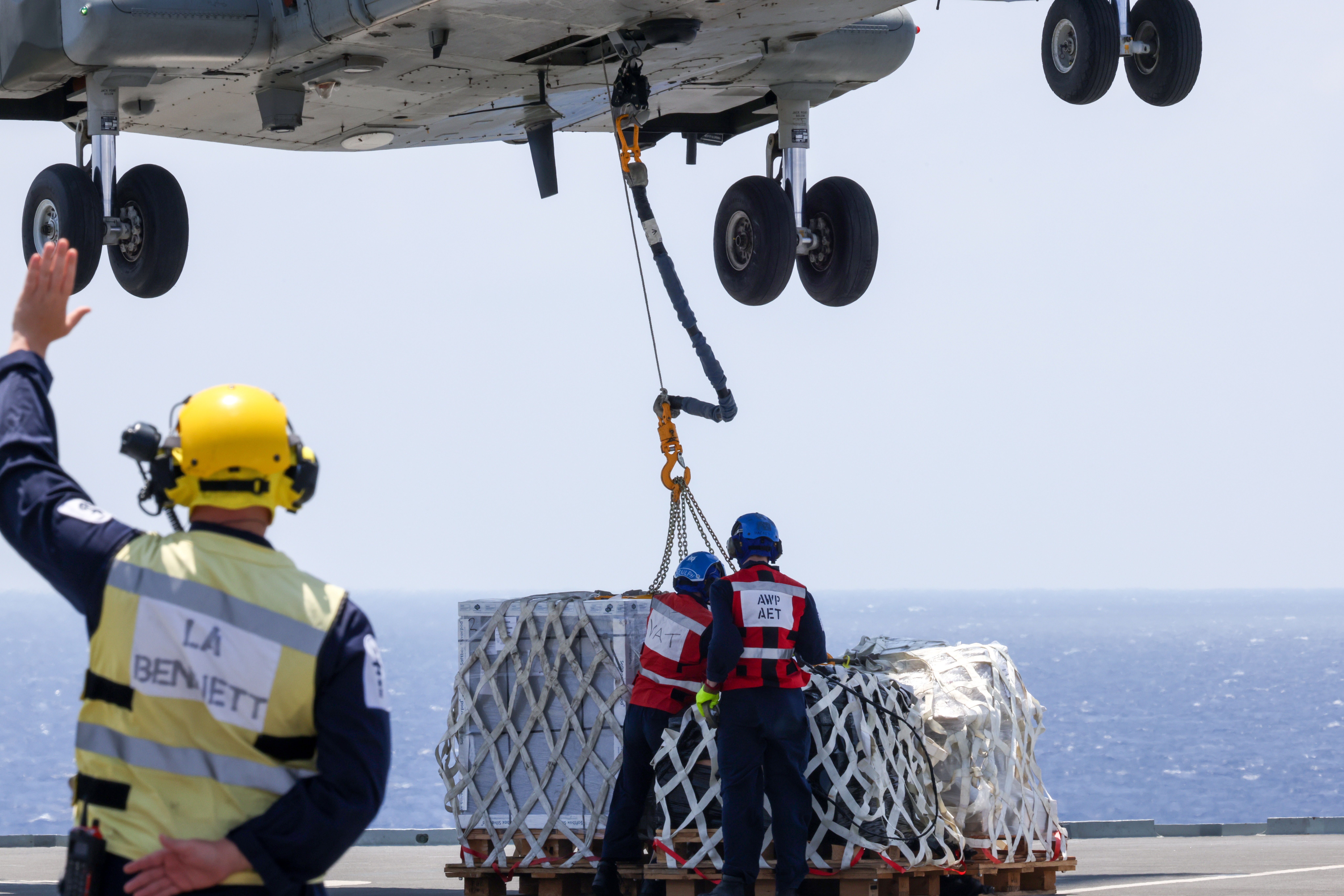 Air Engineers disconnect stores from a Merlin Mk 4 helicopter during a vertical replenishment from RFA Tidespring.