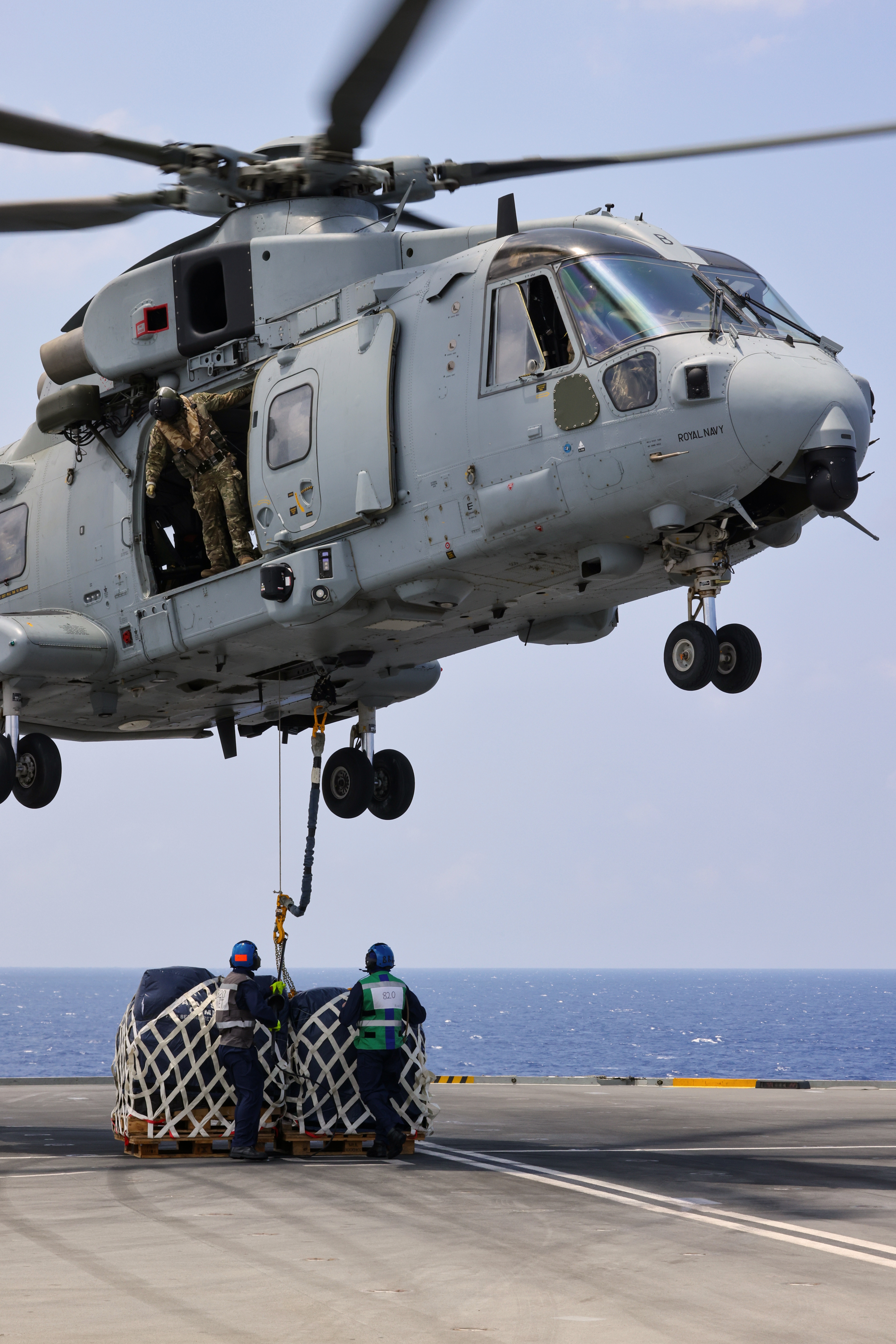 Air Engineers disconnect stores from a Merlin Mk 4 helicopter during a vertical replenishment from RFA Tidespring.