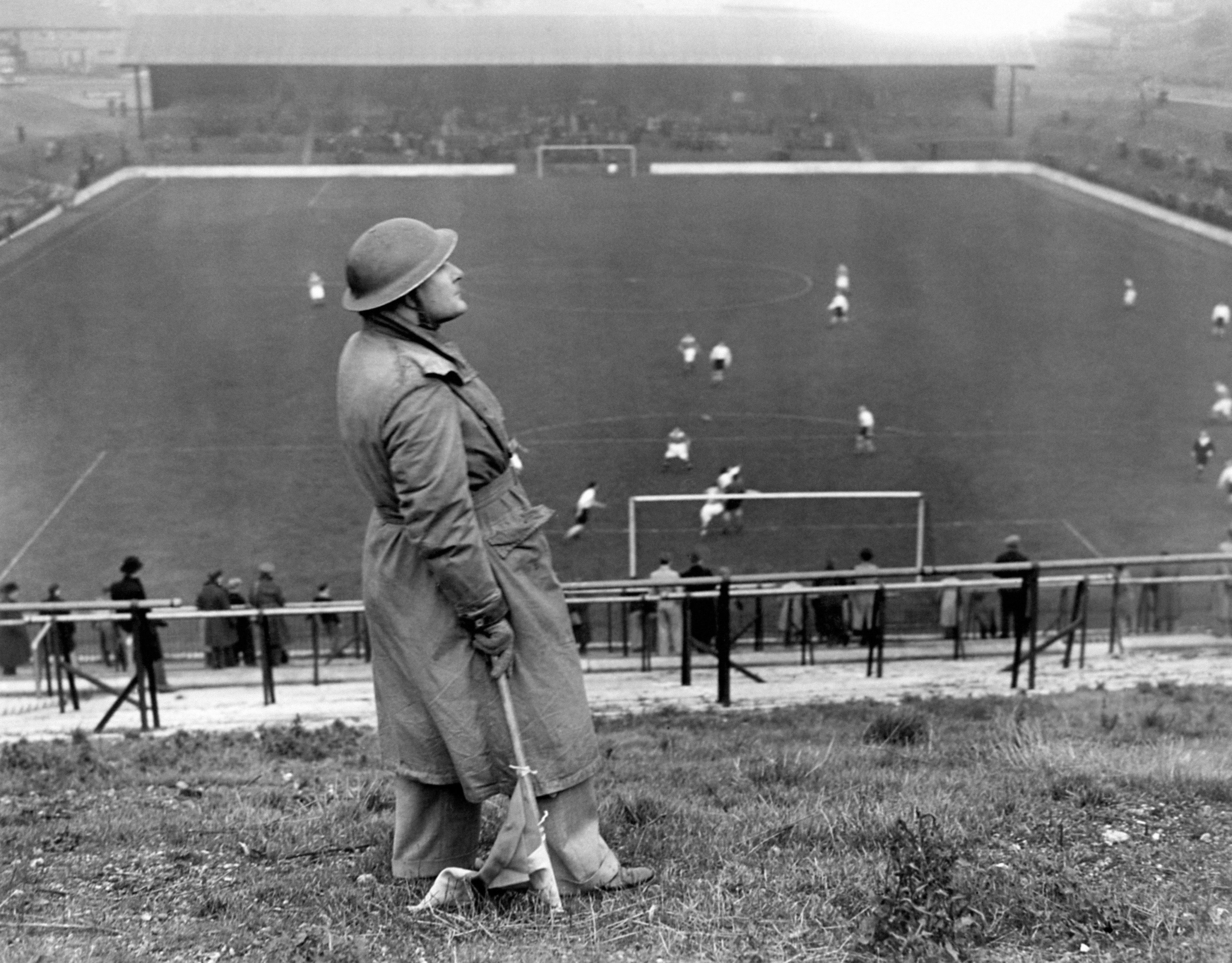 A lookout watches for attack during a football match in WW2. Alamy