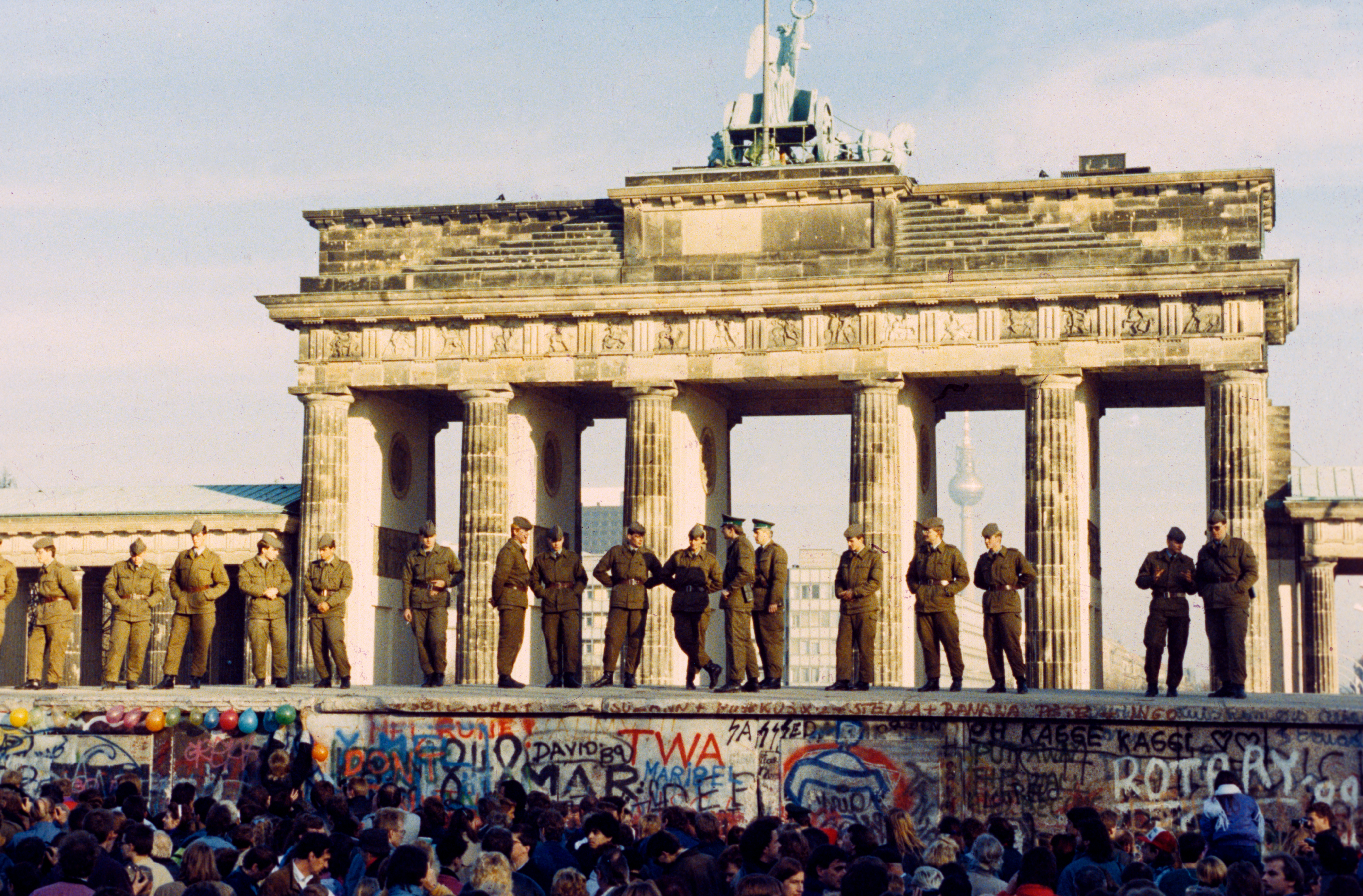 GDR border forces stand on top of the Berlin Wall, in front of the Brandenburg gates