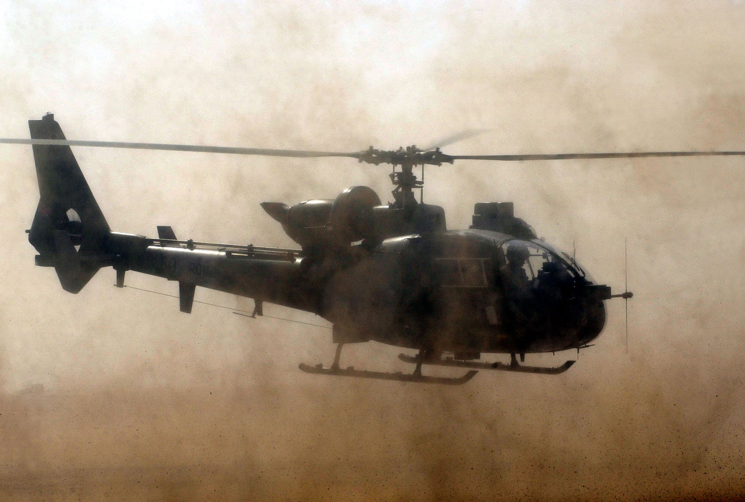 A Royal Marines Gazelle helicopter kicks up a storm at a desert air base
