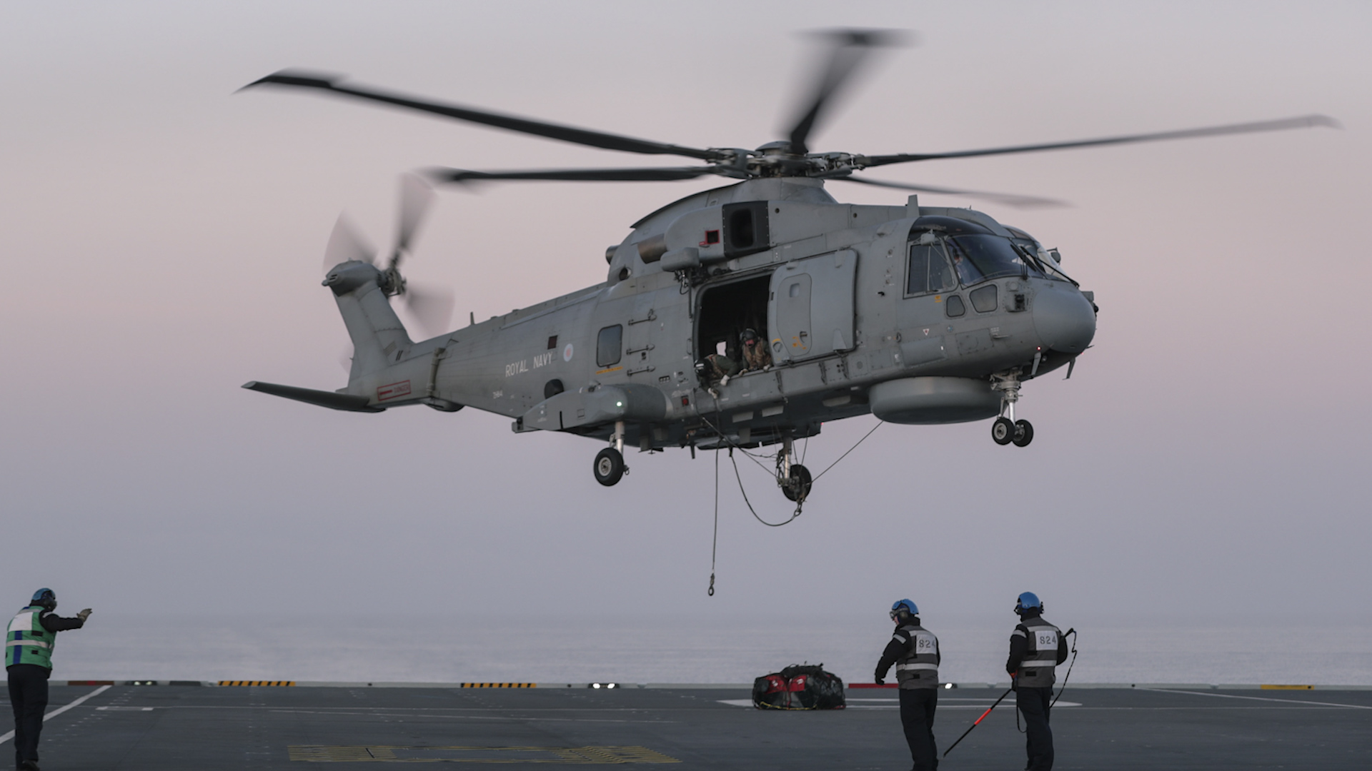 A helicopter from 824 Naval Air Squadron hovers above HMS Queen Elizabeth (Picture: Royal Navy LPhot Belinda Alker).