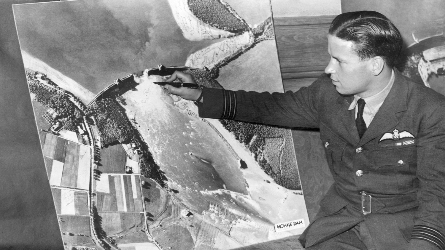 Image ID B5EXHH Dambusters Raid Wing Commander Guy Gibson, Commanding Officer of No 617 Squadron, puts his signature on the map showing the destruction of the Mohne Dam 22 June 1943 CREDIT Trinity Mirror / Mirrorpix / Alamy Stock Photo EXP 01.06.2024
