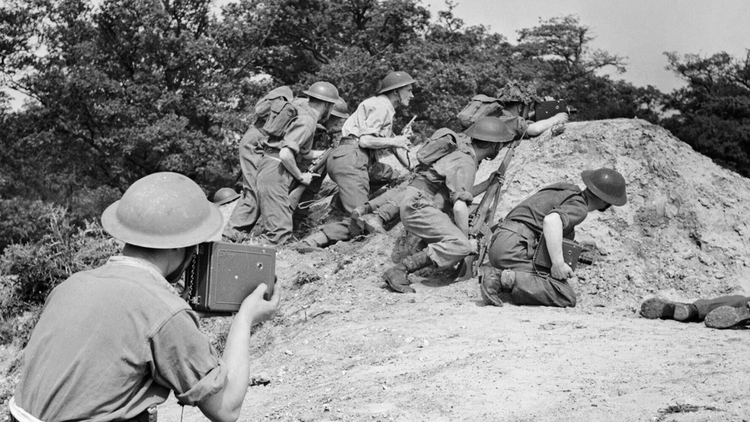 Image ID 2JRFMAN The last phase of training for the Army Film and Photographic Unit takes place at a Battle School. A cameraman films an infantry section sheltering behind a small mound of earth CREDIT piemags / Alamy Stock Photo EXP 15.02.23